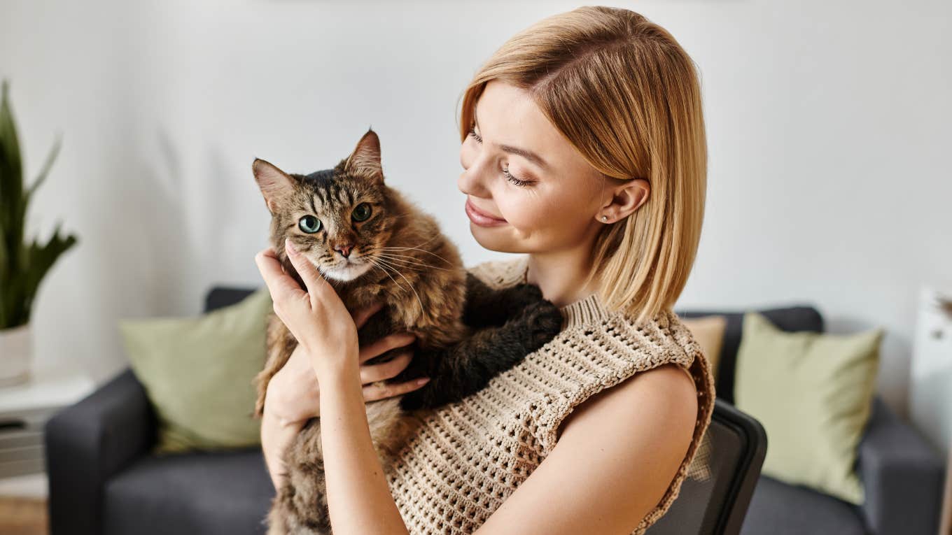 Things That Make Pets Quietly Judge You, According To Research smiling woman holding her judgmental cat