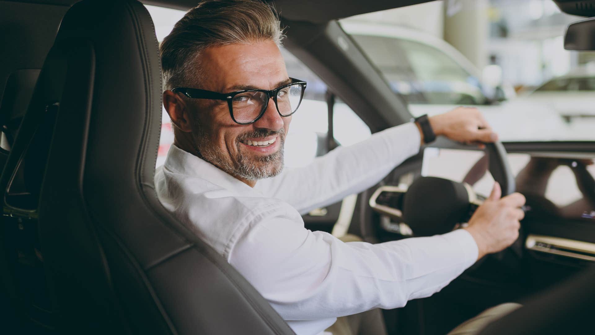 Man smiling and driving a flashy car.