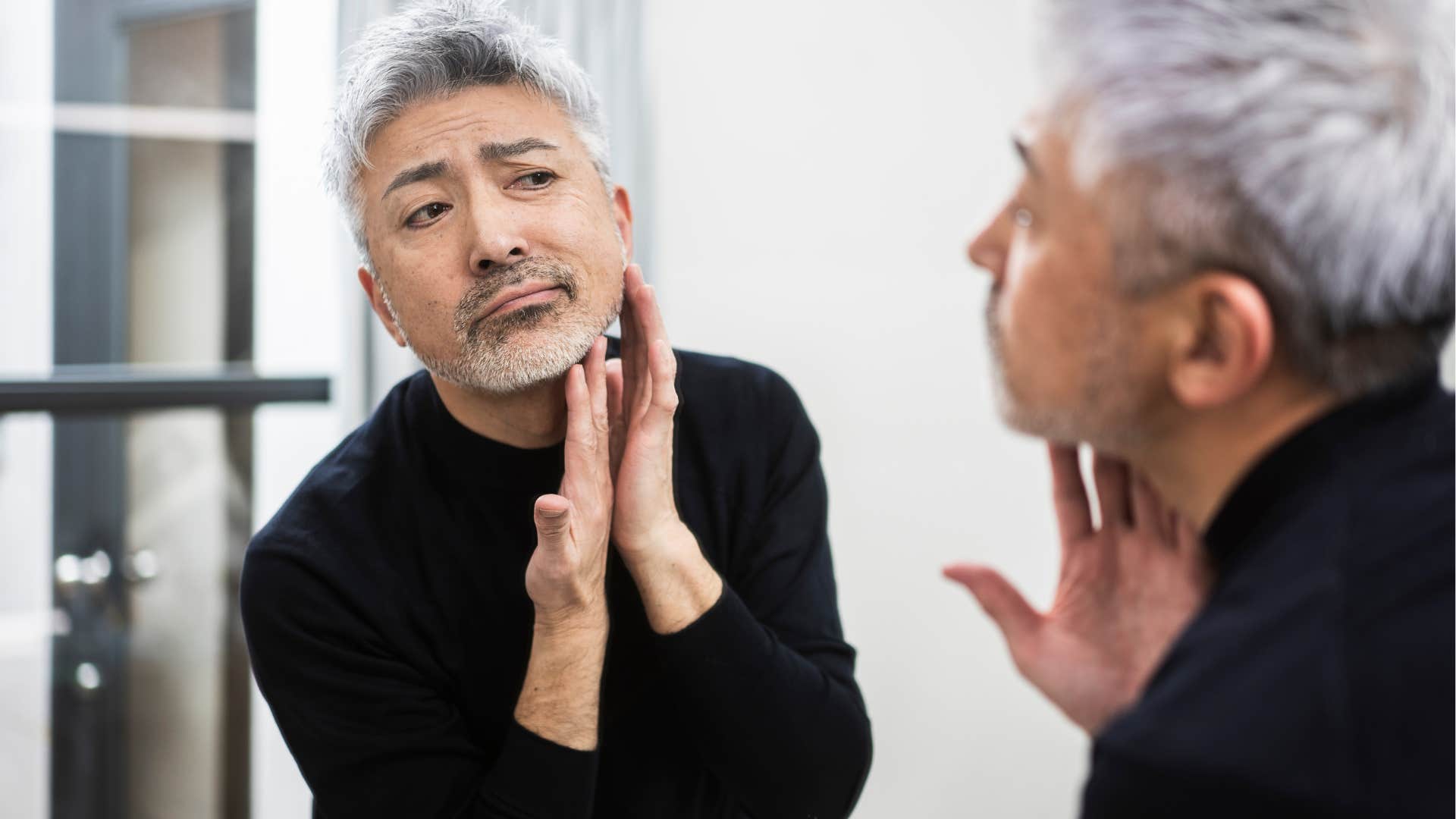 Man who doesn't care about looking young staring in a mirror.