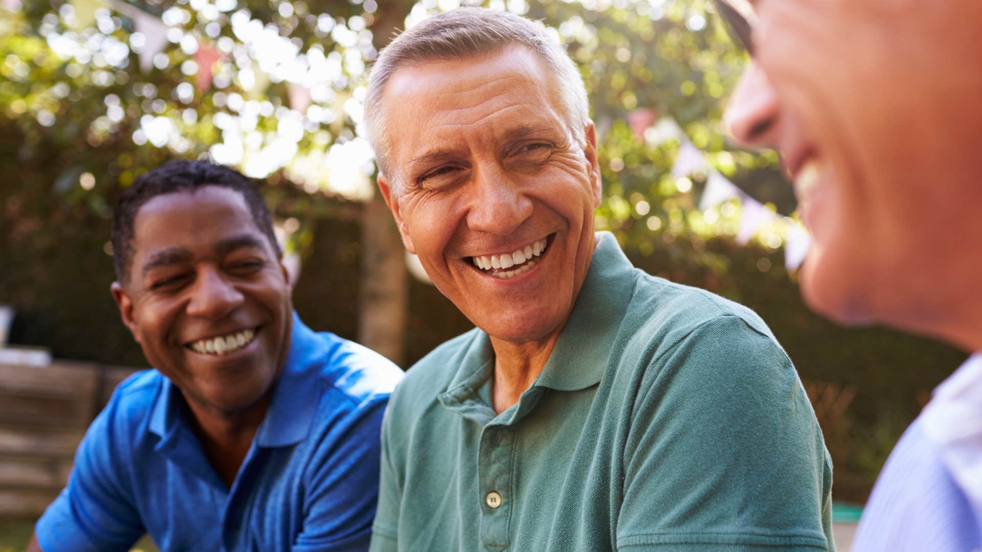 Man smiling and trying to fit in around his friends.