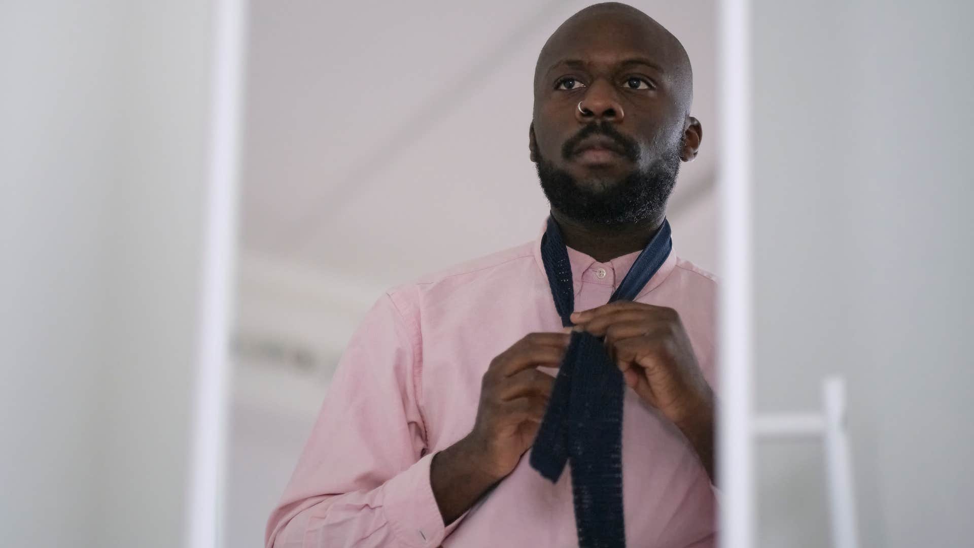 Man who doesn't care about following all the clothing trends looking in a mirror.