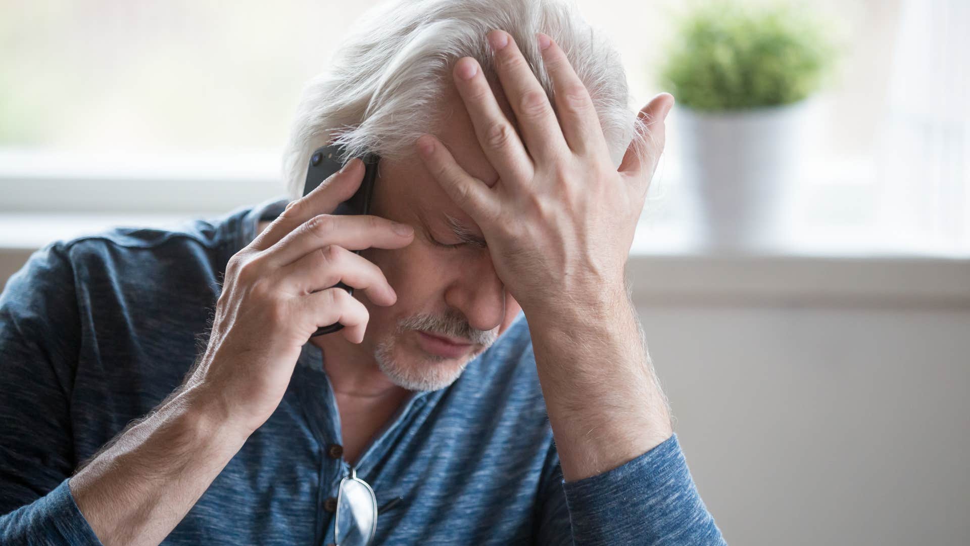 Upset man saying "you're overreacting" on the phone.