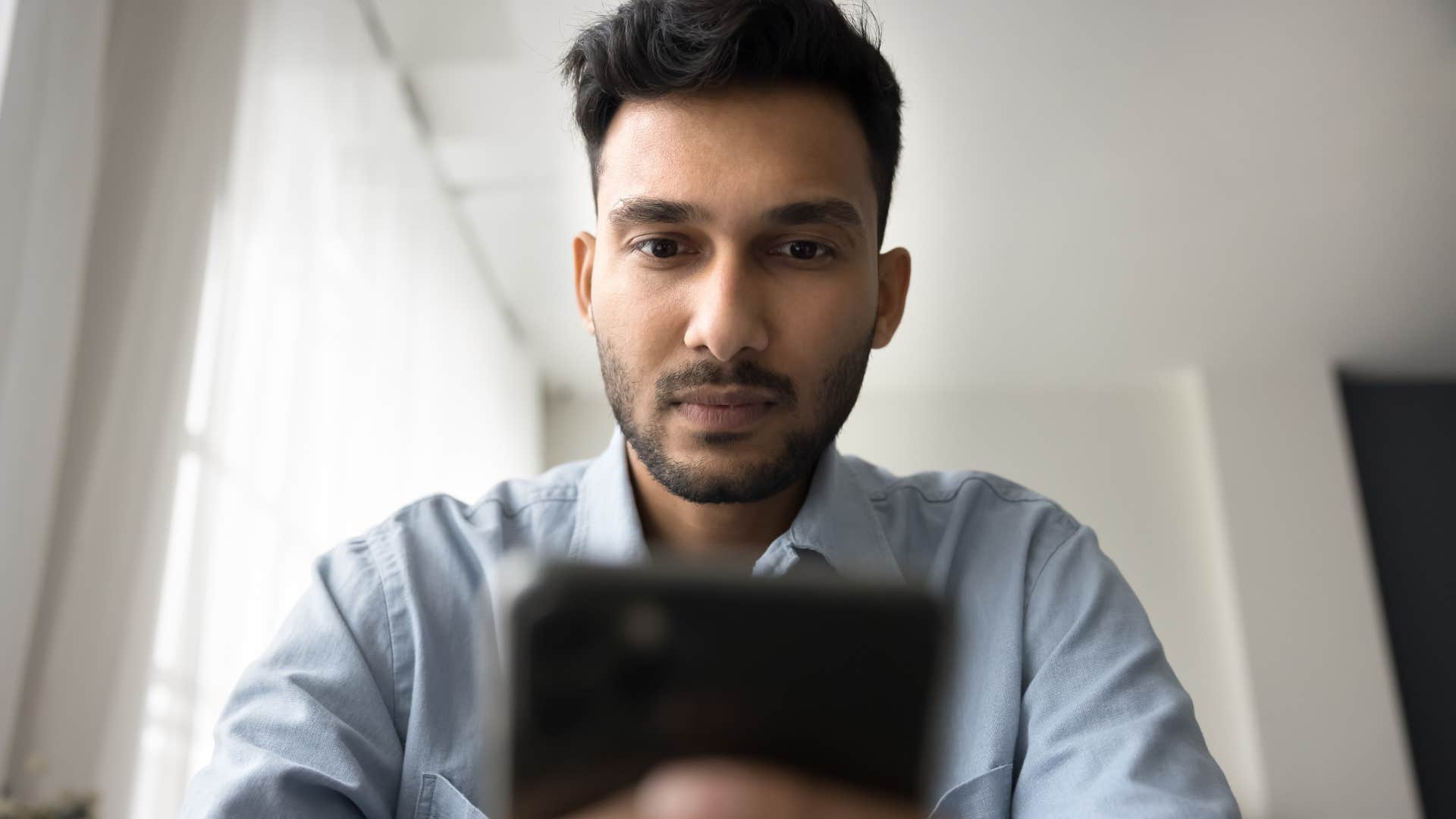 man on his phone looking at everyones posts but not liking anything