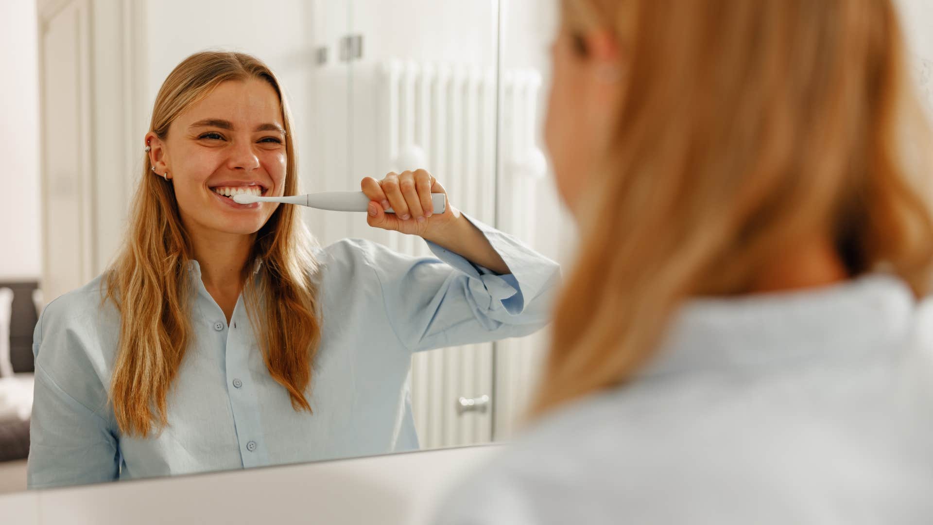 woman brushing her teeth in modern bathroom