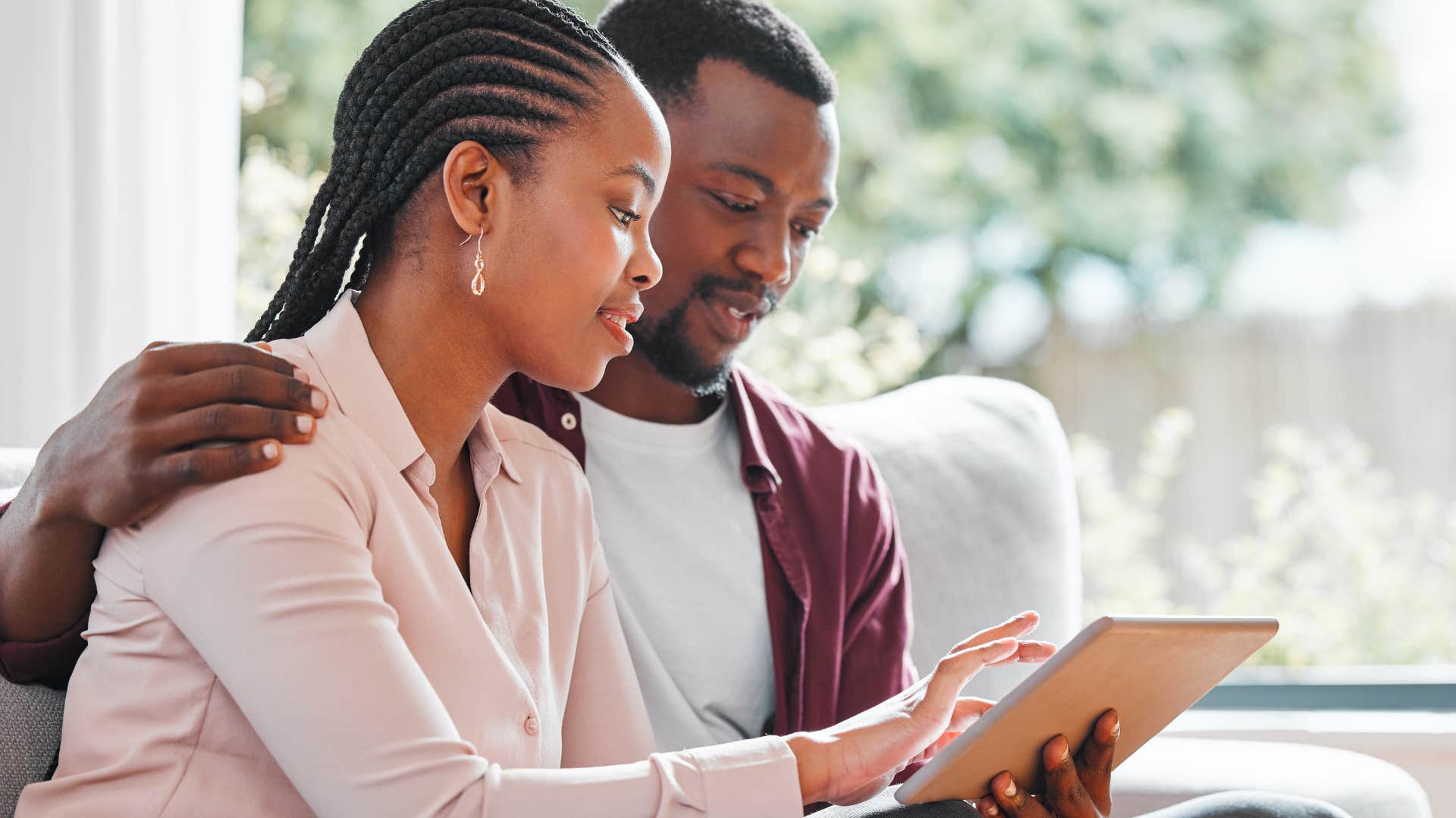 man with lots of technology in his home looking at a tablet with his partner
