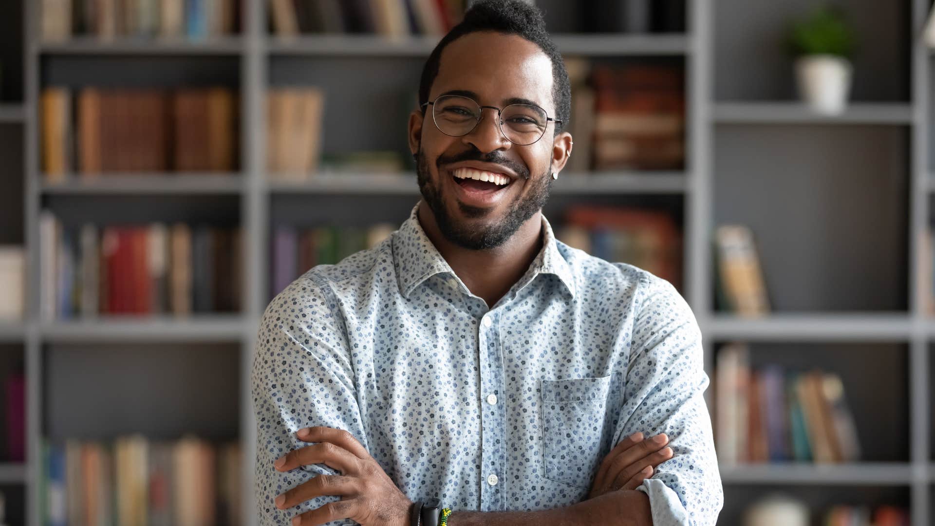 Man smiling in front of his books at home.