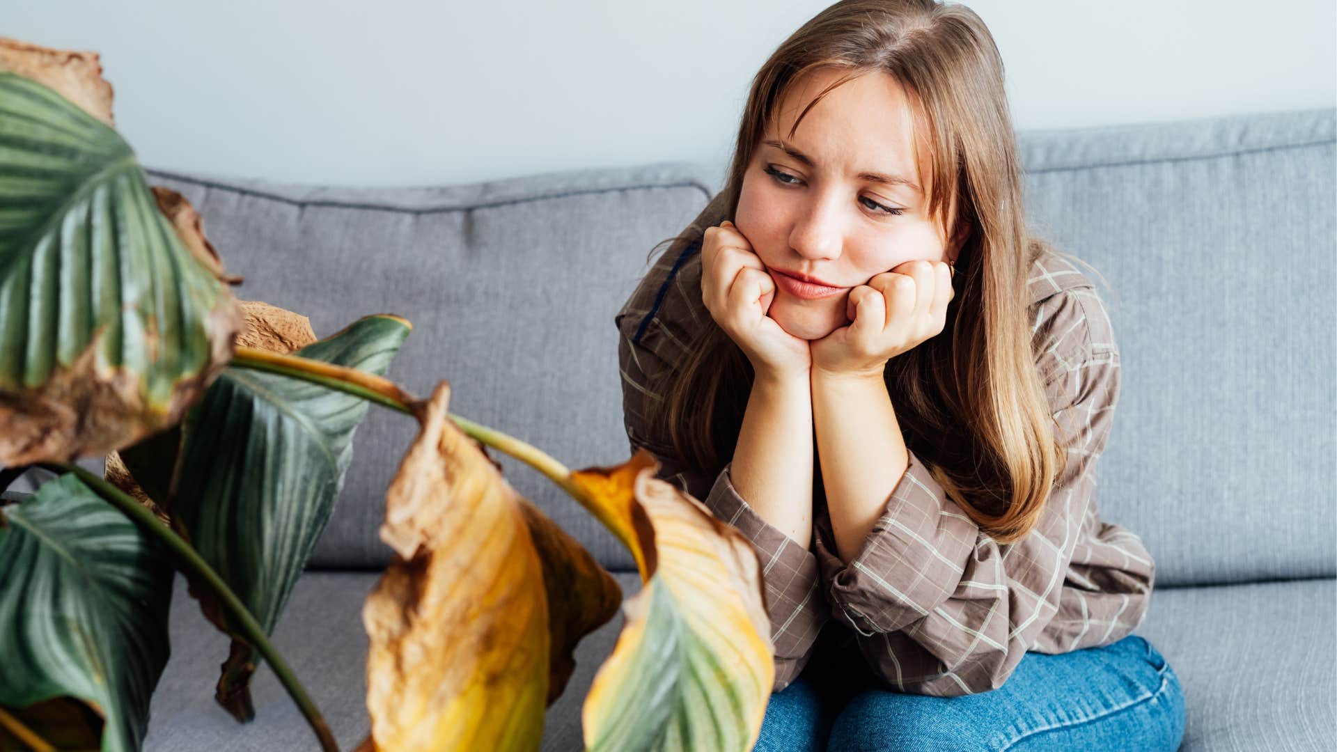 Woman looking at dead plants or flowers at home.