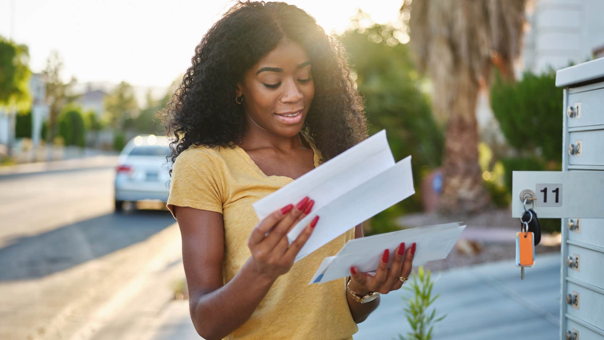 Woman looking through piles of mail outside.