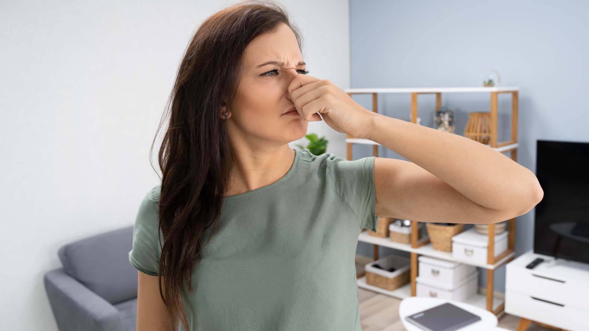 Woman holding her nose for a bad smell at home.