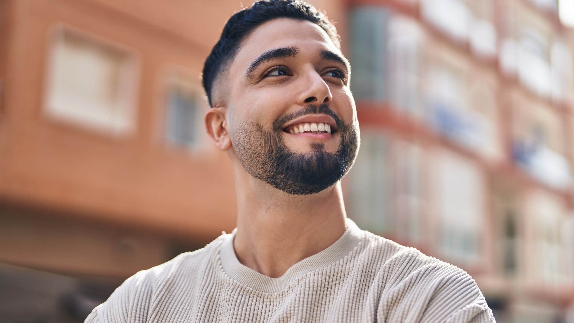Man who's more open-minded smiling outside.