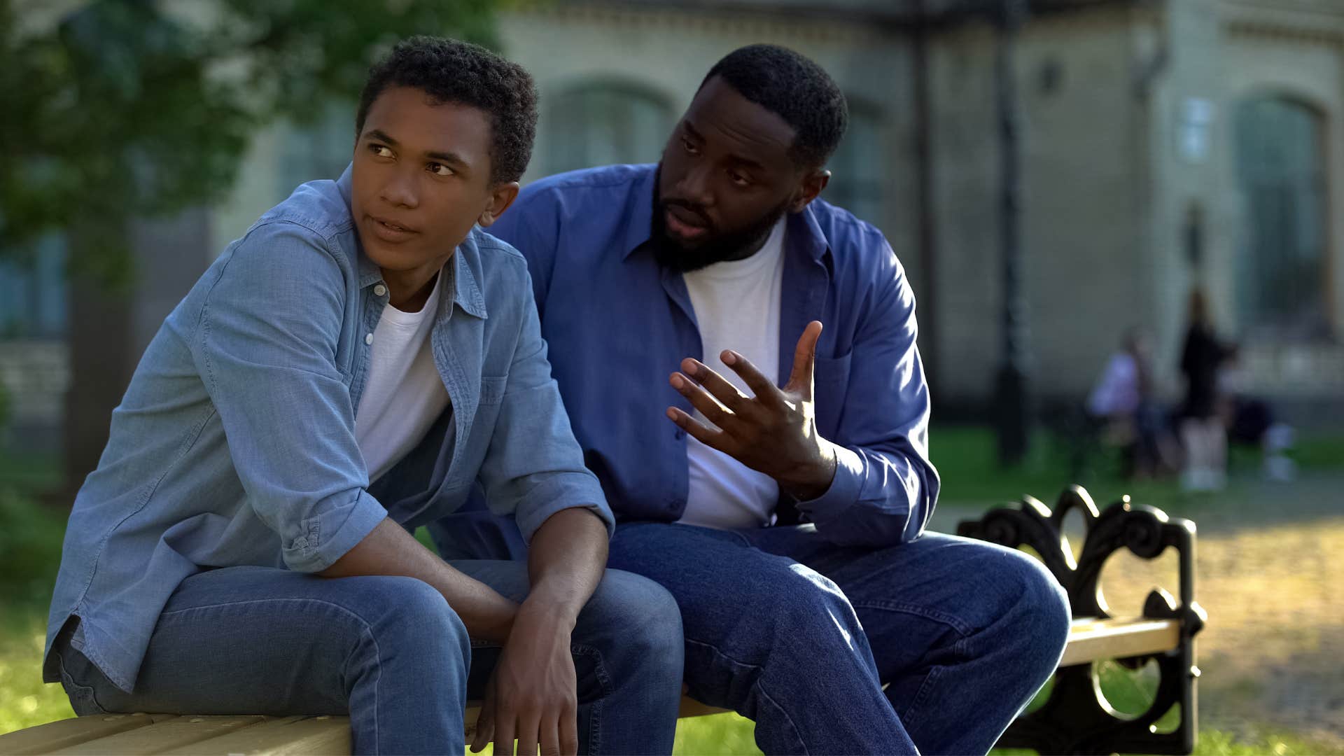 man in dark blue shirt telling son how'd that work out for you as they sit on the bench