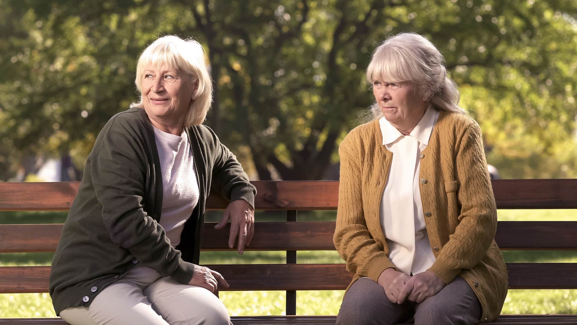 two older women sitting on the bench saying you look comfortable while being judgemental