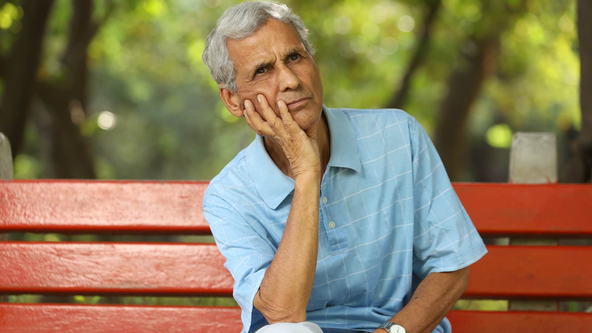 Man who's ignoring a gut instinct sitting on a park bench.