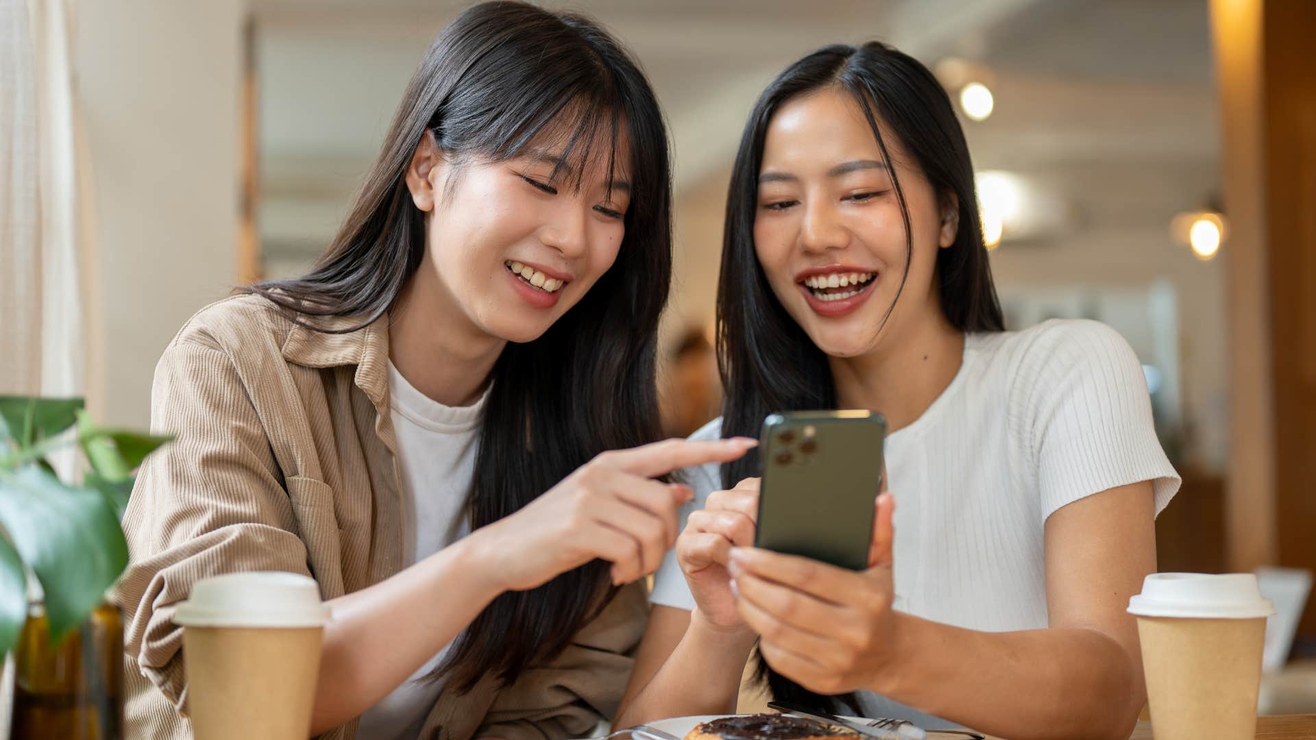 Two women smiling and leaving their drinks unattended at a coffee shop.