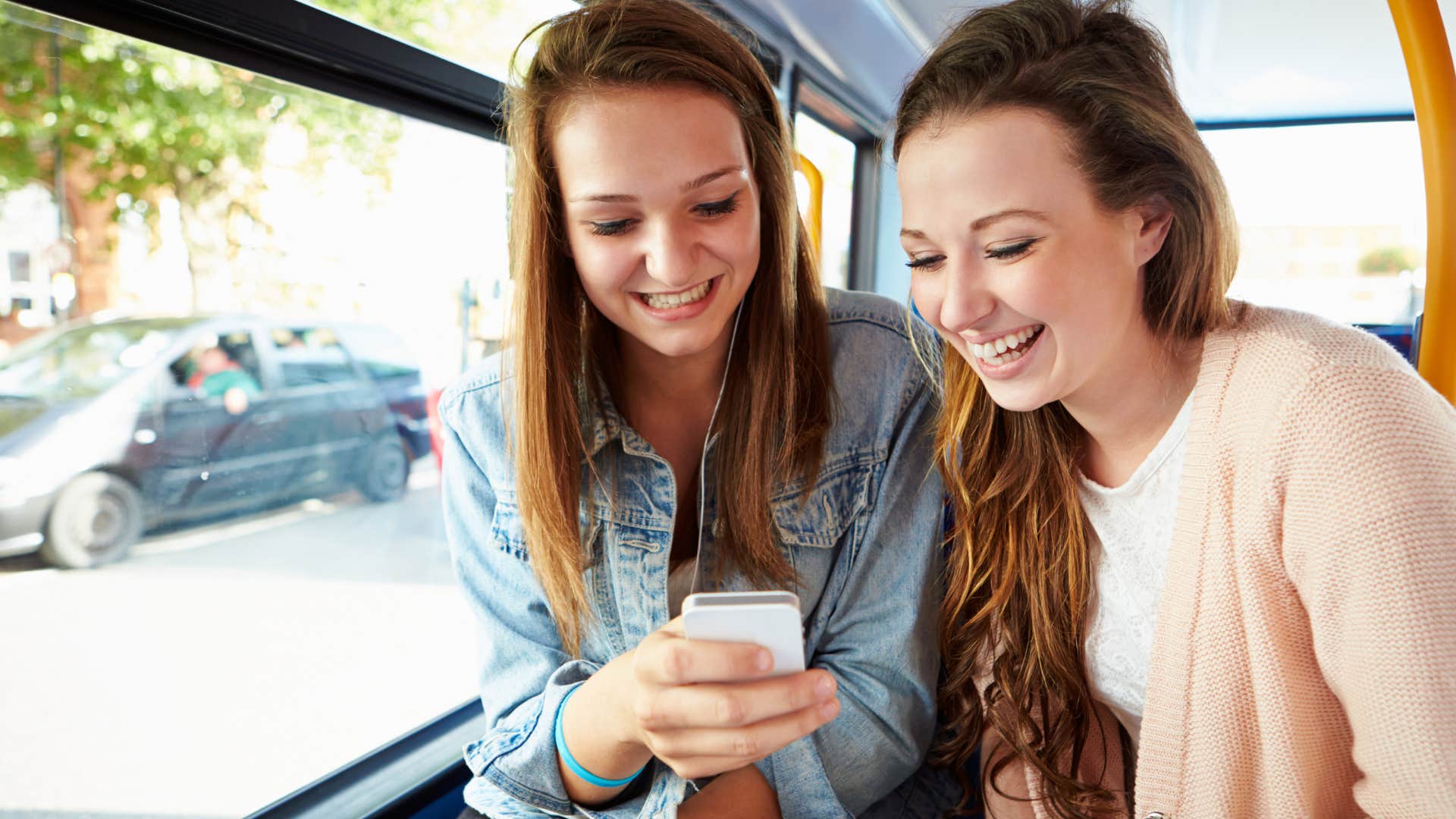 Woman who's trusting people too quickly smiling next to a friend on a bus.