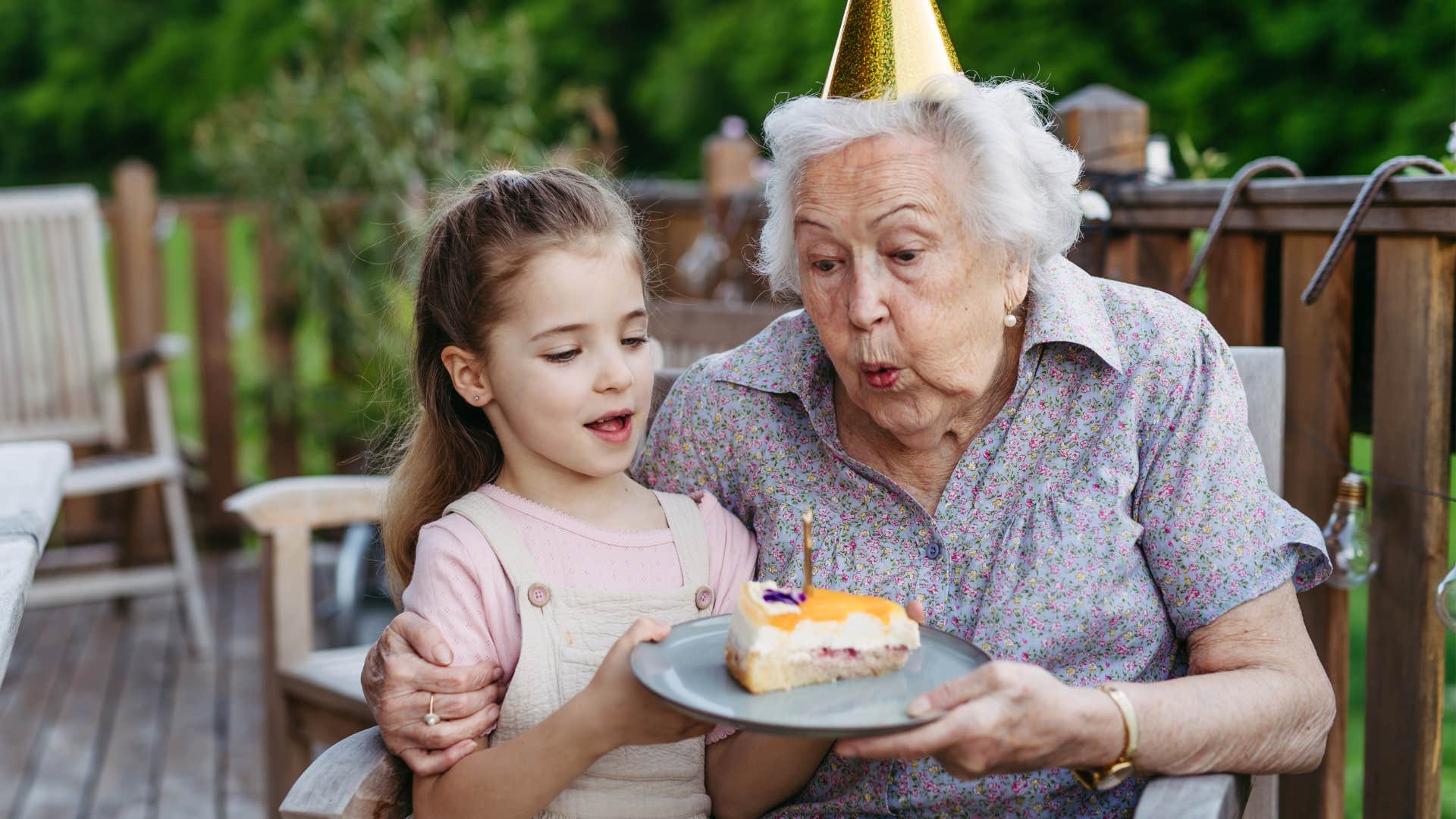 woman blowing out birthday candles with her granddaughter
