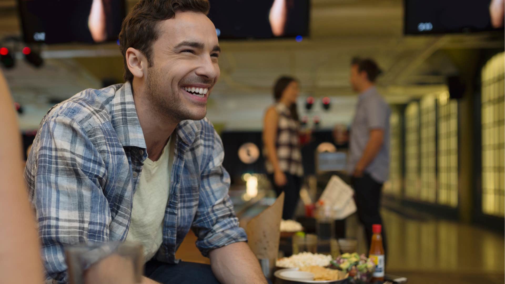 man smiling and eating while bowling with friends