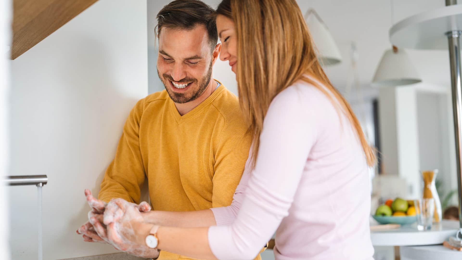 woman washing their hands in the bathroom with her partner