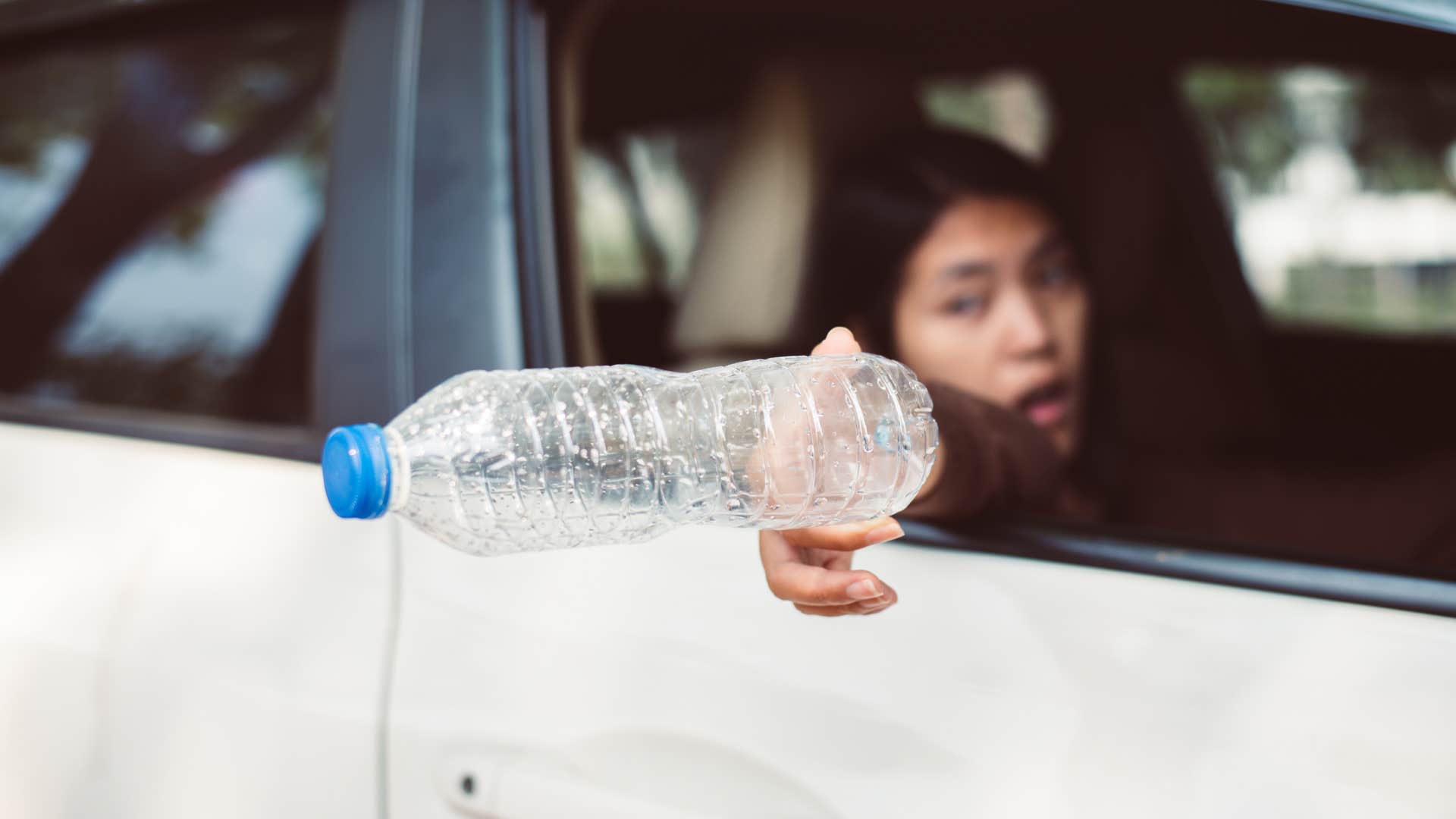woman with dirty car tossing trash out the window