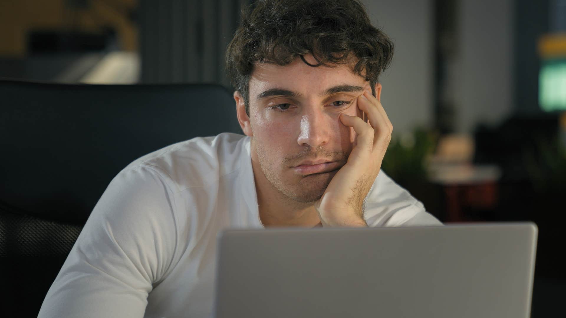 man experiencing burnout working overtime on his laptop
