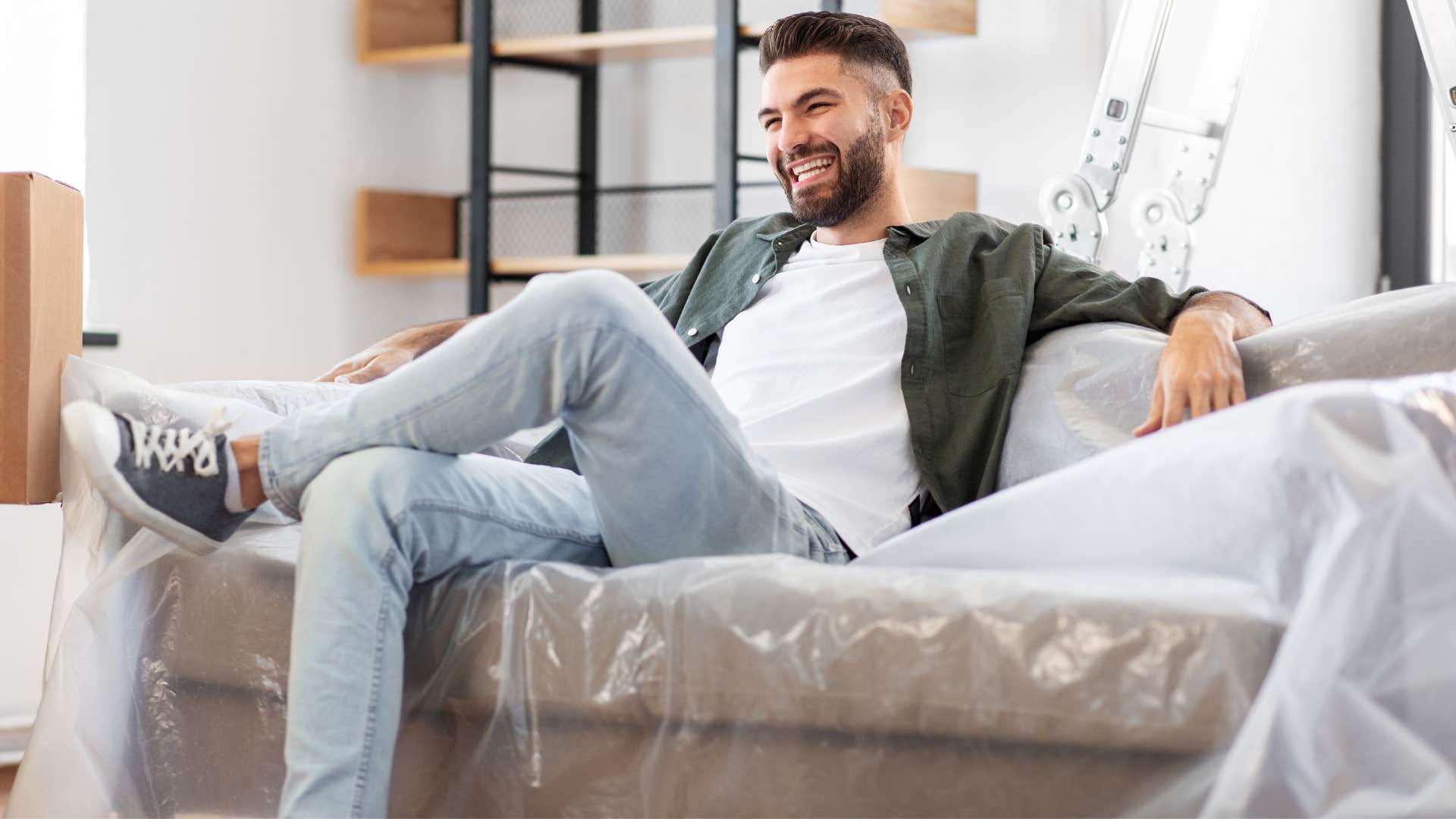 a man sits on his grandparents plastic covered couch to keep it clean