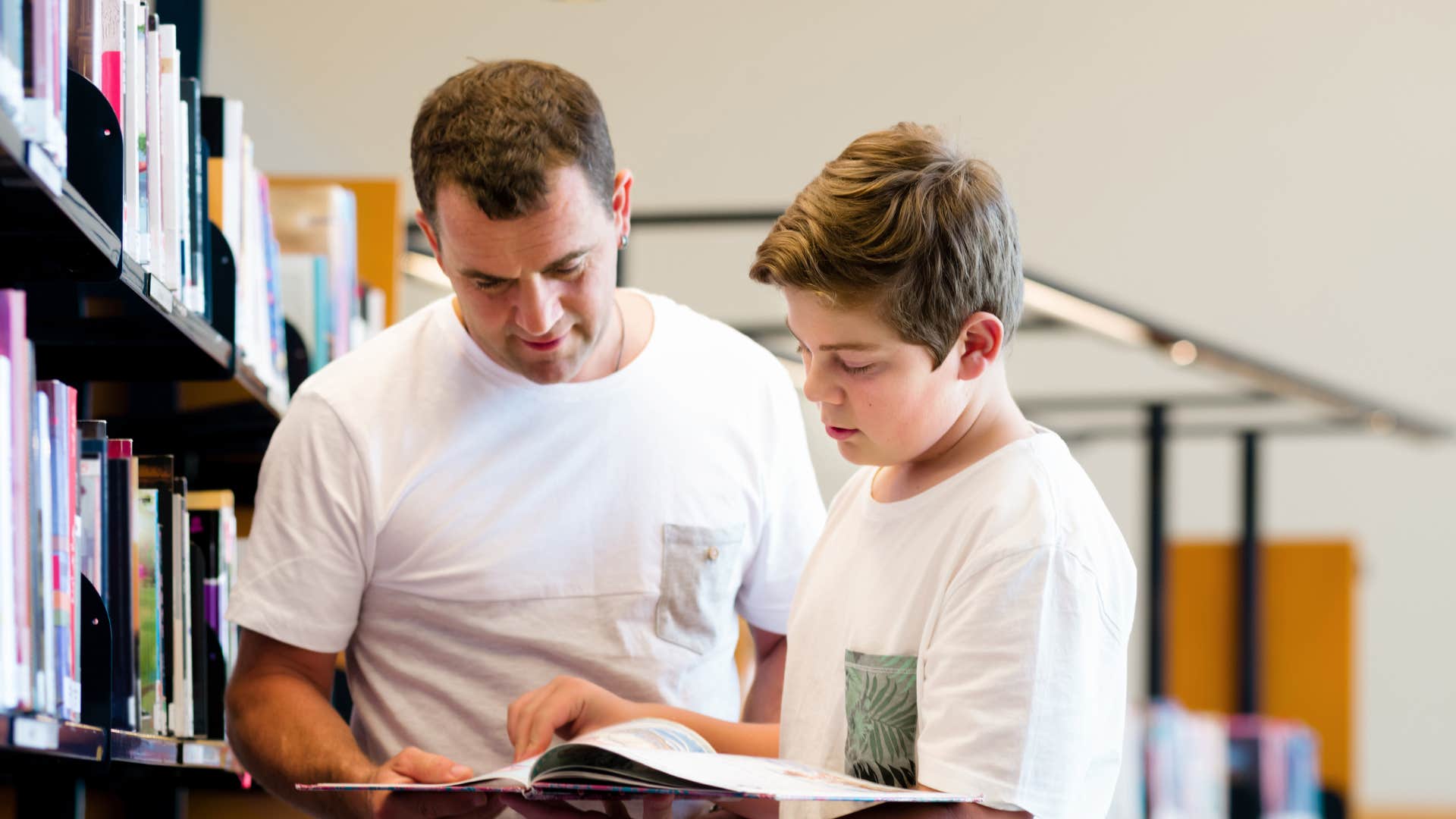 gen x father showing his son how to do research in physical books
