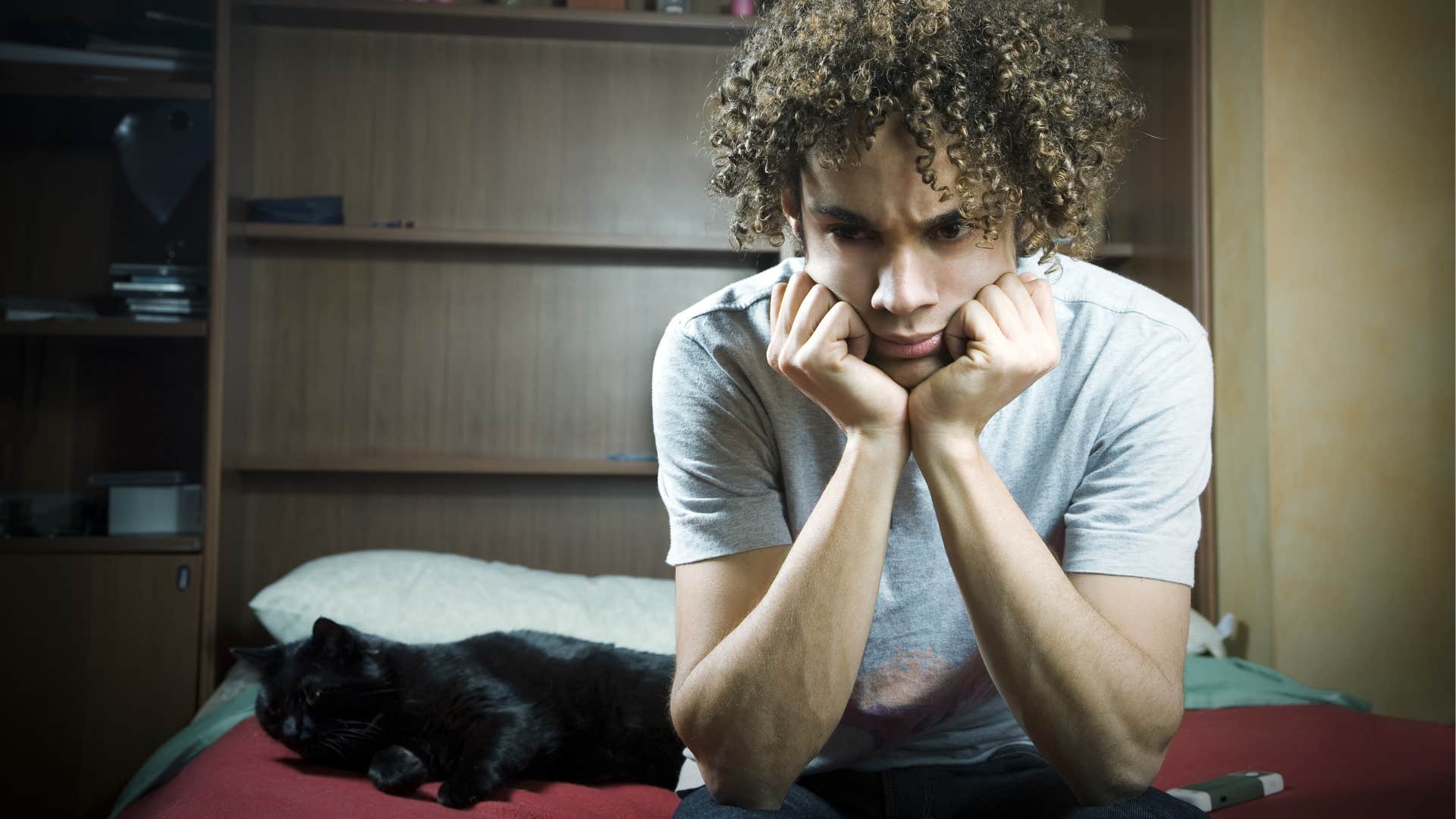 teenage boy ignoring cat not giving him attention or affection