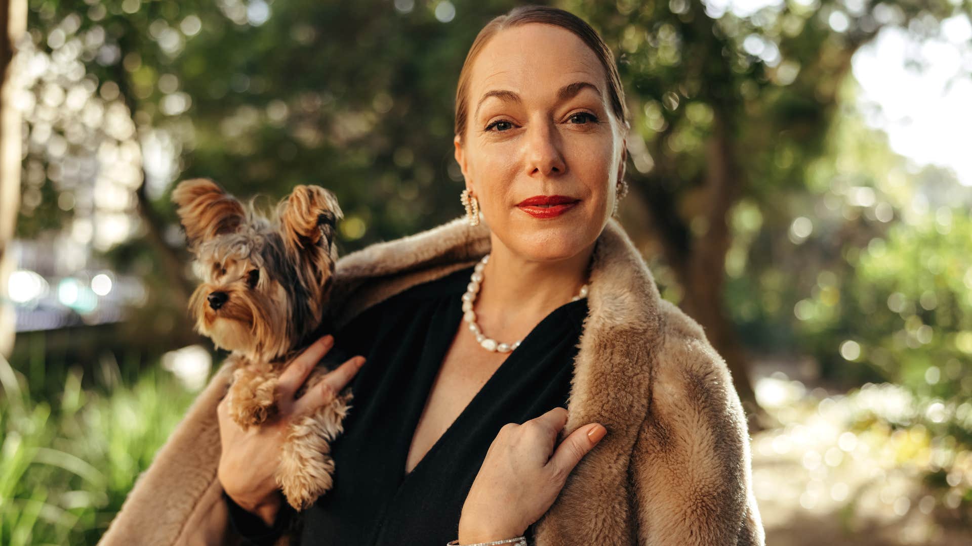 a wealthy woman wears over the top clothing while strolling through central park