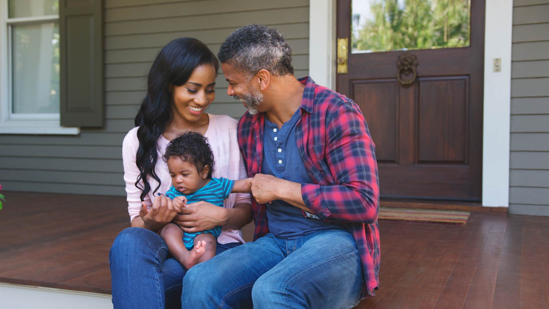 couple and infant relax on porch