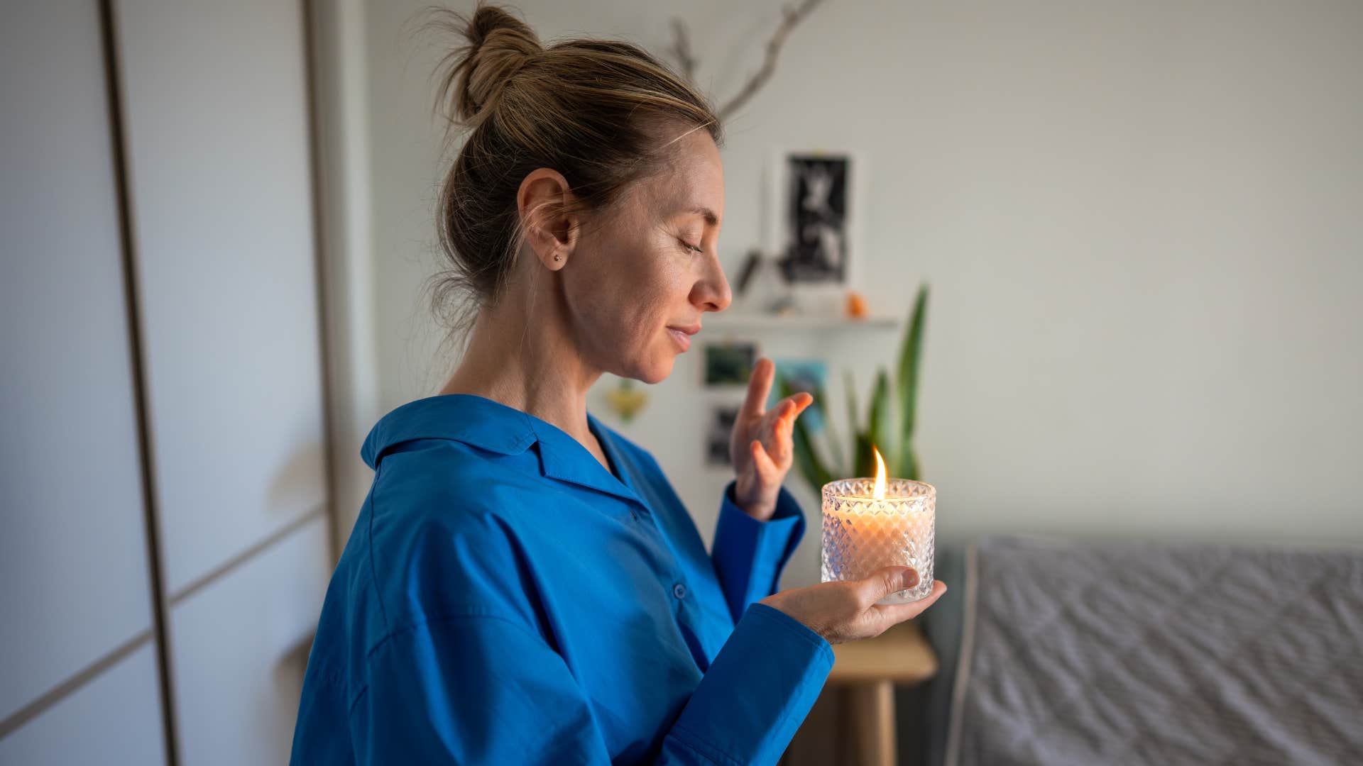 a woman burns a candle in her home to give off a great scent before her guests arrive