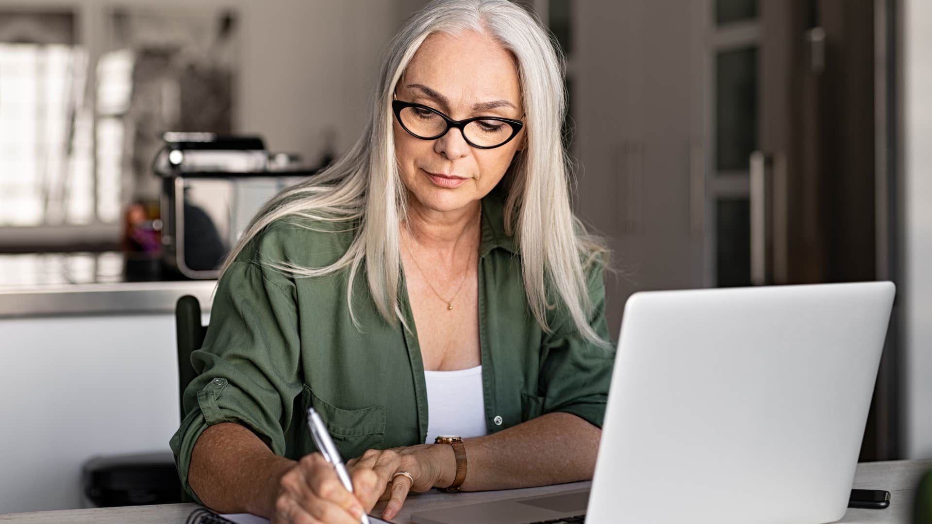 Woman gratitude journaling at home in a notebook.