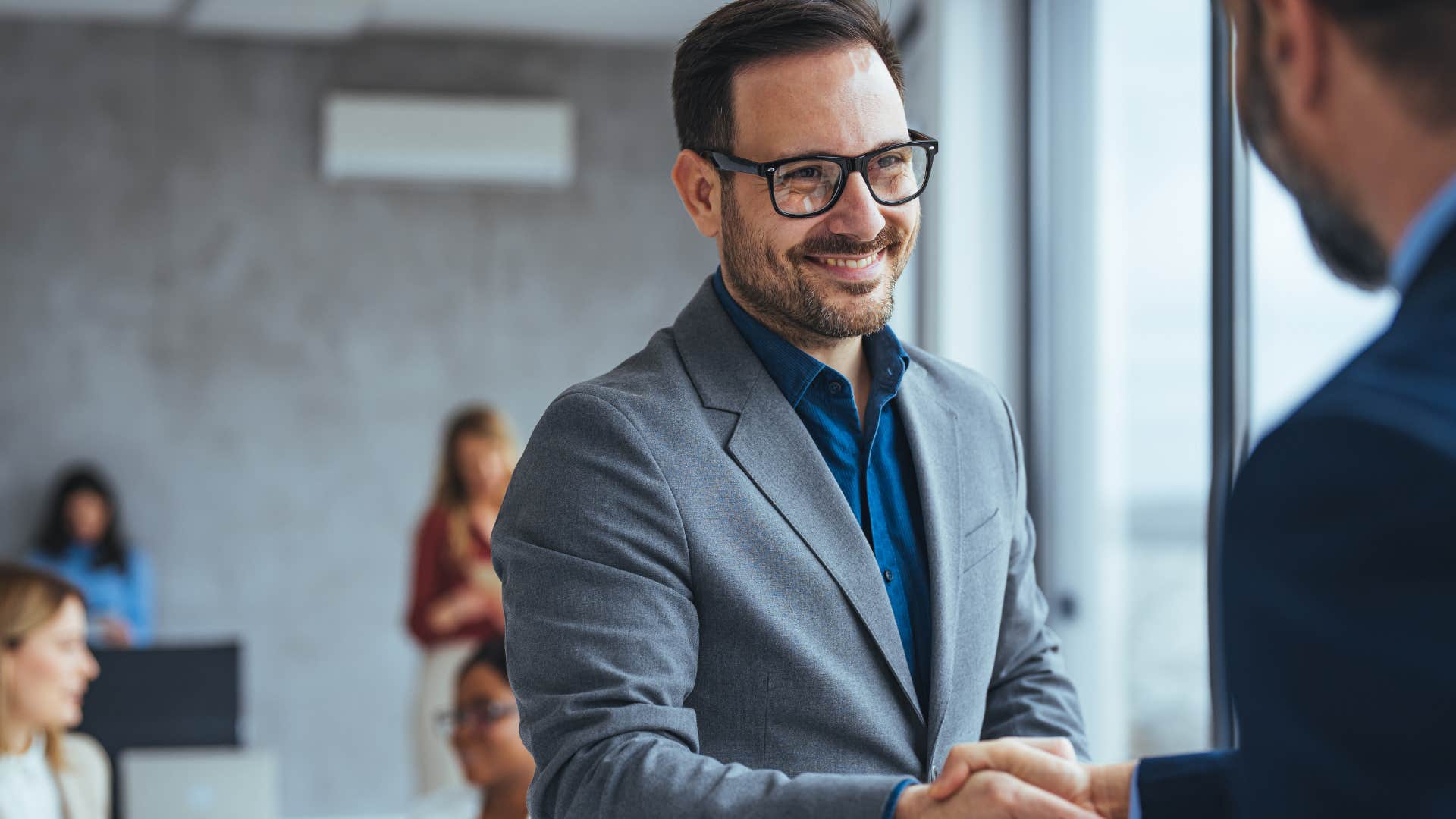 Man smiling and shaking someone's hand at a networking event.
