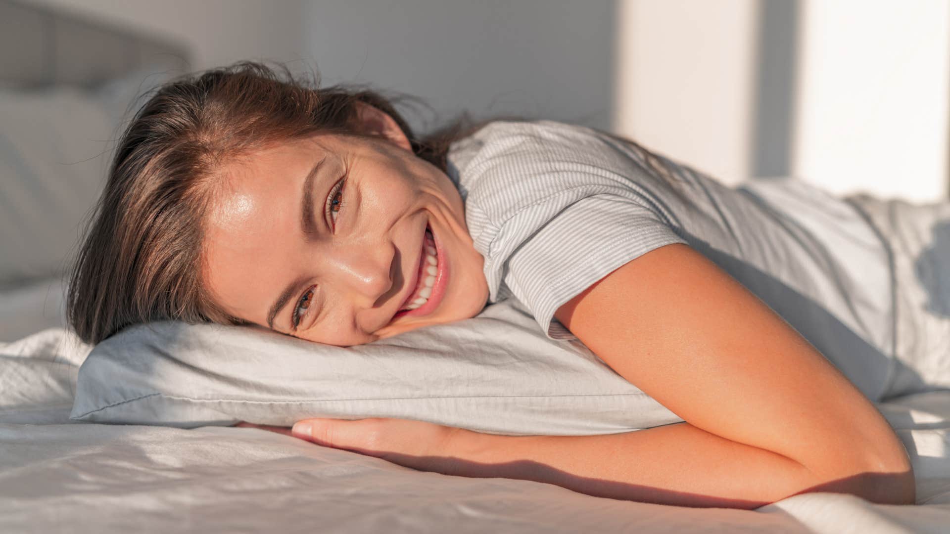 happy woman laying in bed not worrying about what she cant control