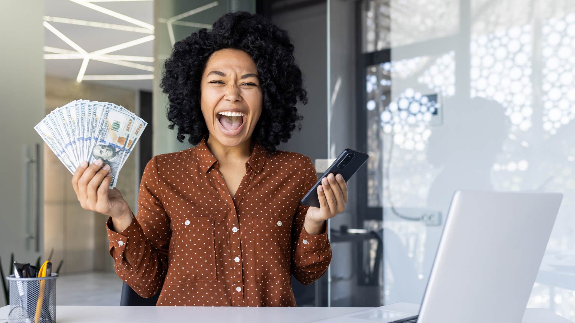 smiling woman holding a wad of cash