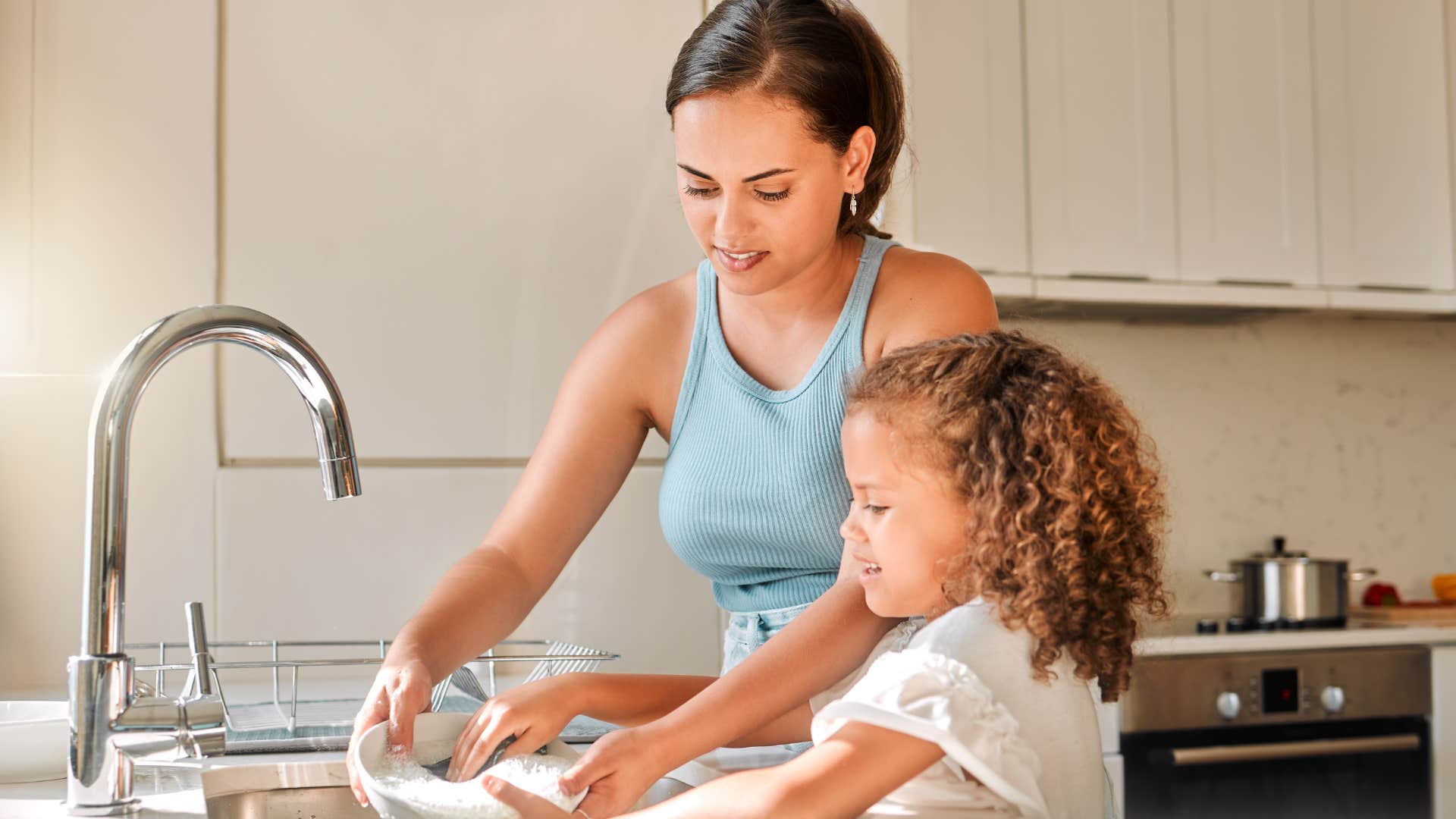 woman without dishwashers washing dishes by hand with daughter