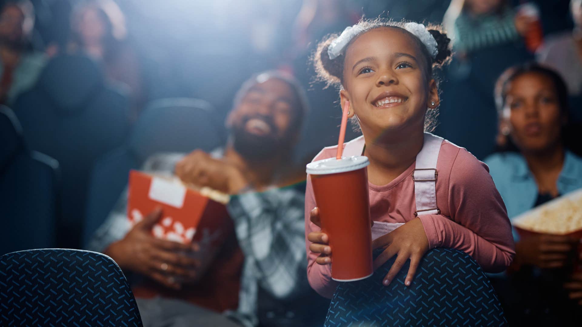 little kids smiling while at the movies with their parents