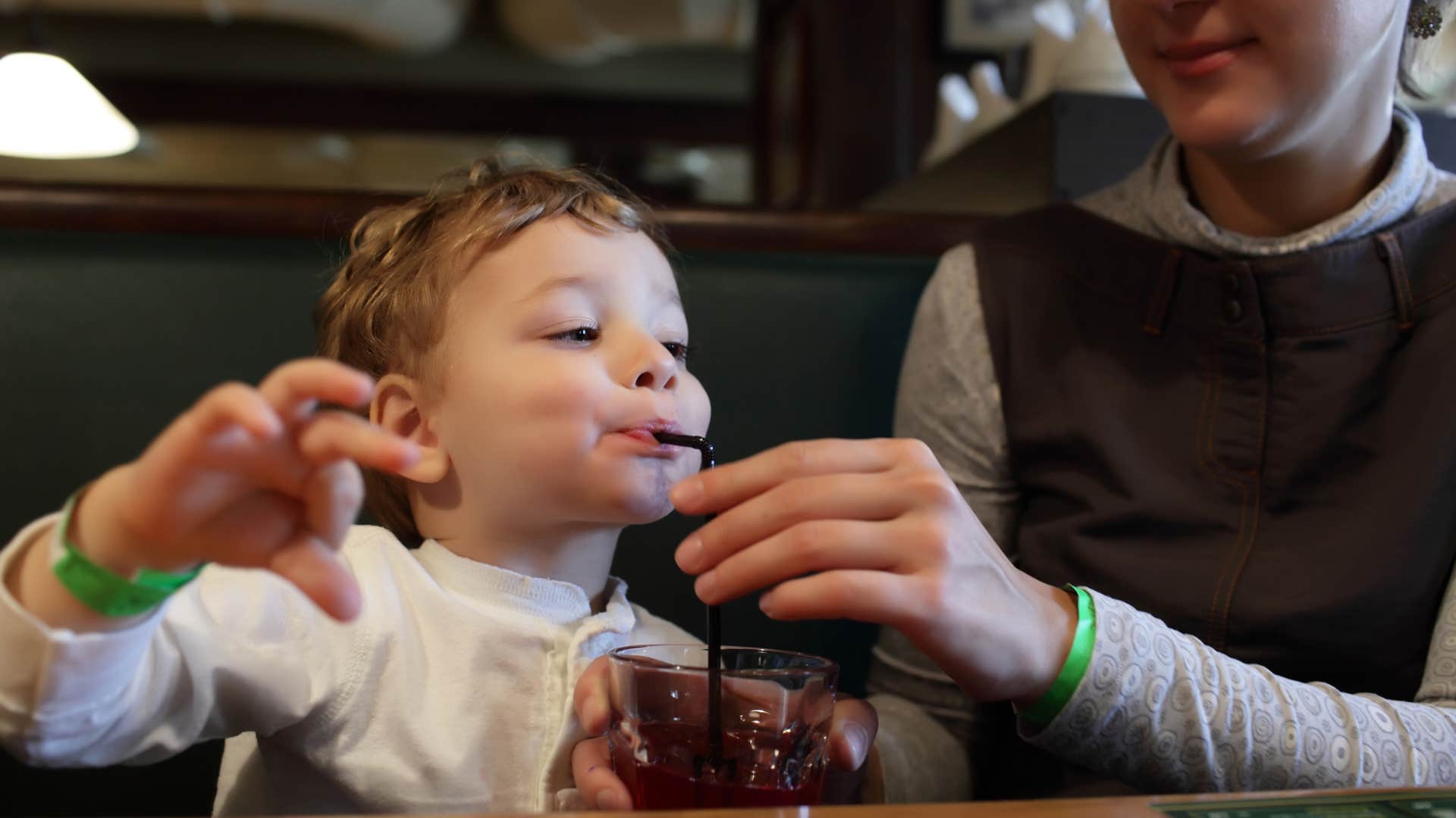 kid drinking a soda after ordering drinks at a restaurant