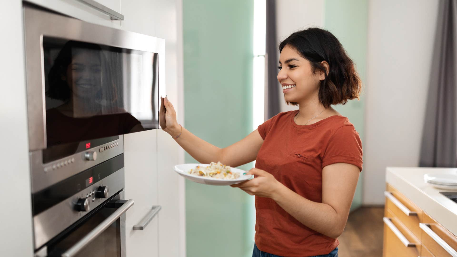 a young woman heats up left over because her gen x parents never taught her how to cook