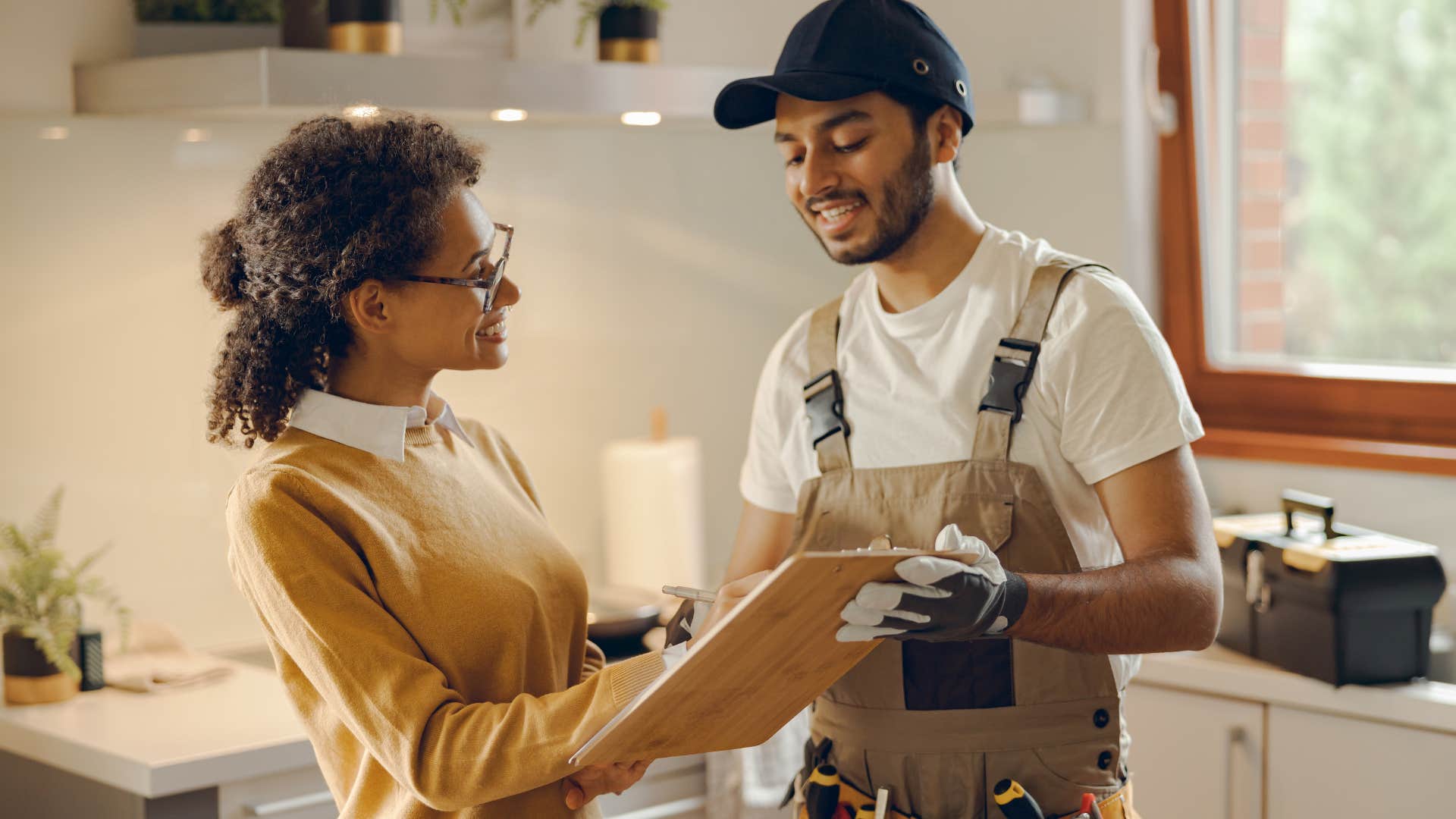 woman smiling at repairman fixing broken appliances