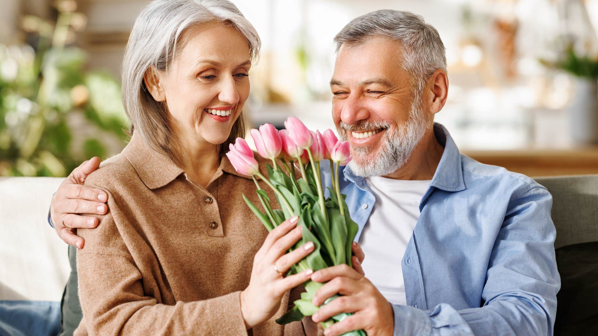 couple smelling fresh flowers on their couch