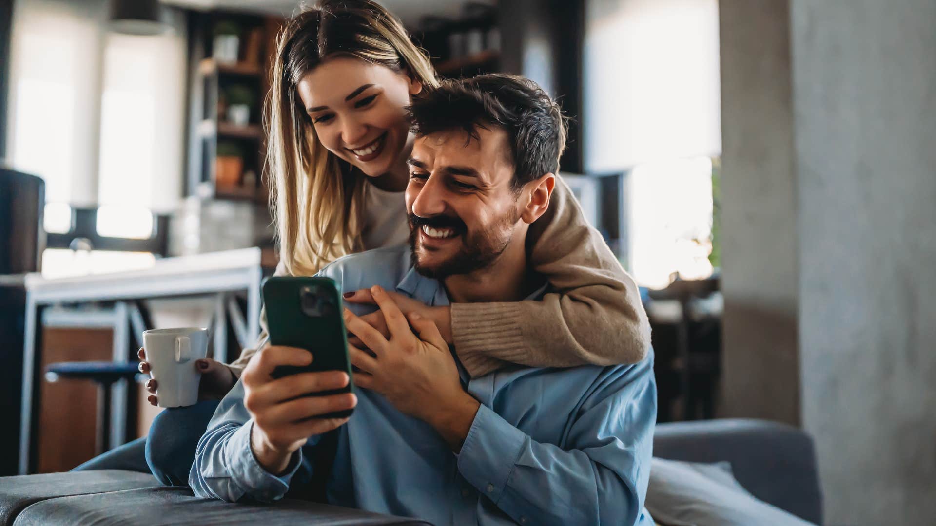 couple who keeps your social spaces open smiling in their living room