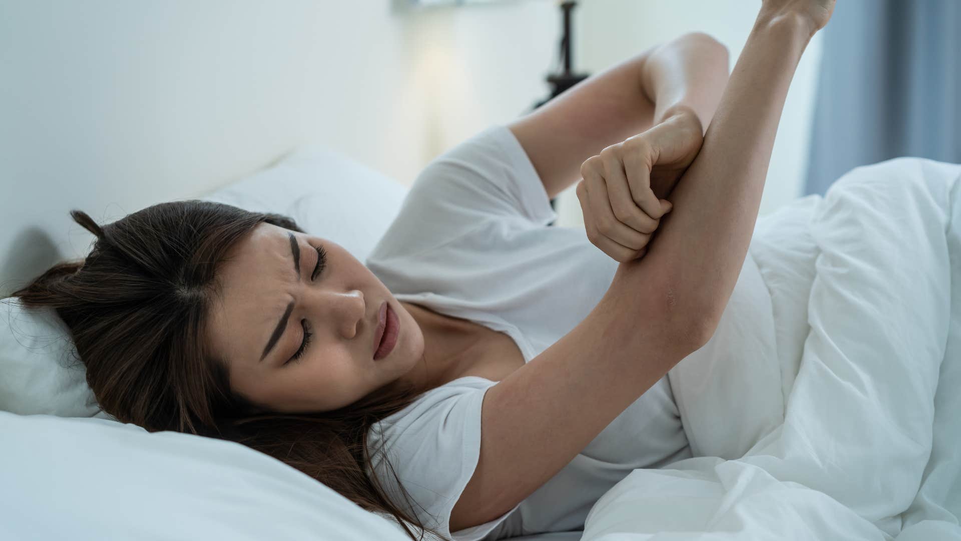 woman scratching her arm feeling itchy