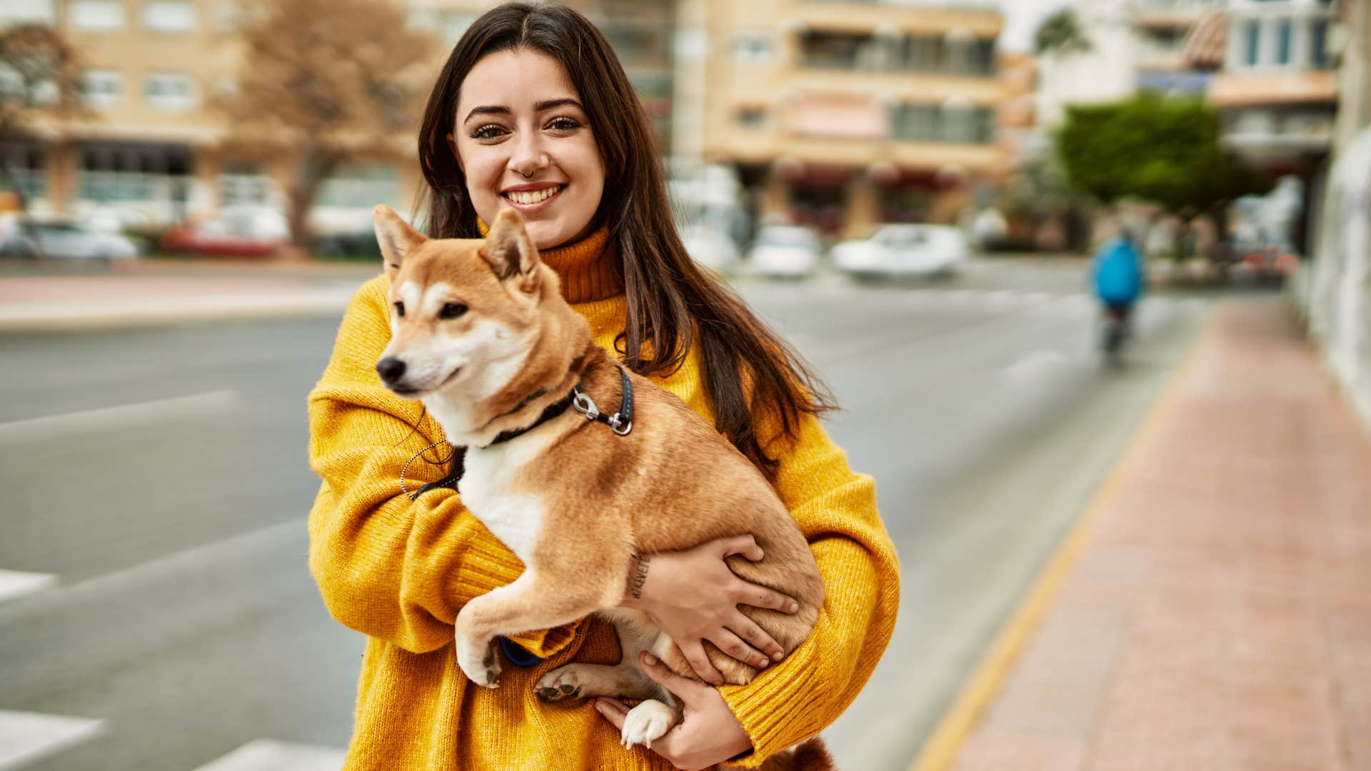 woman holding dog in the street