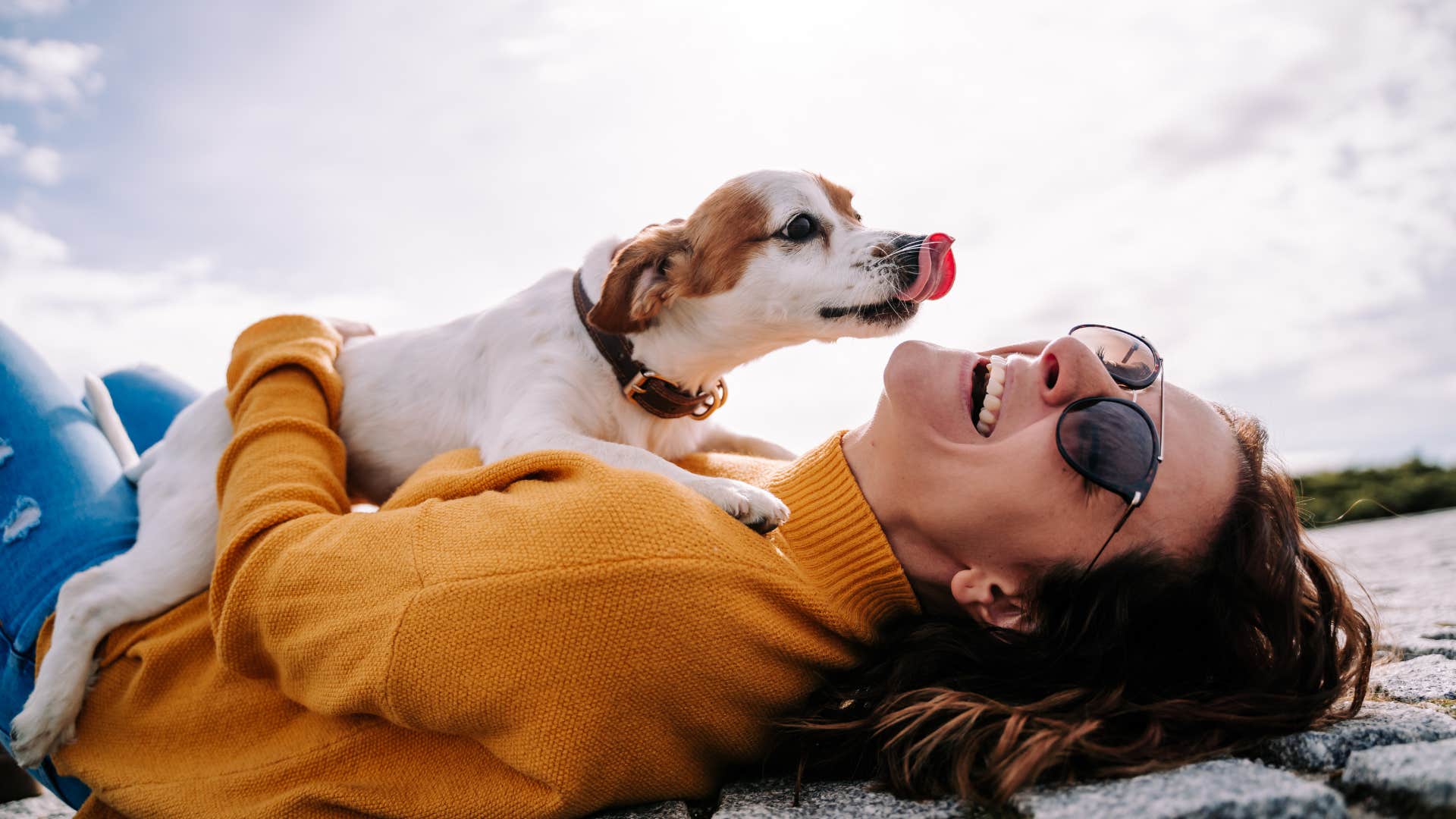 woman laughing while holding dog outside