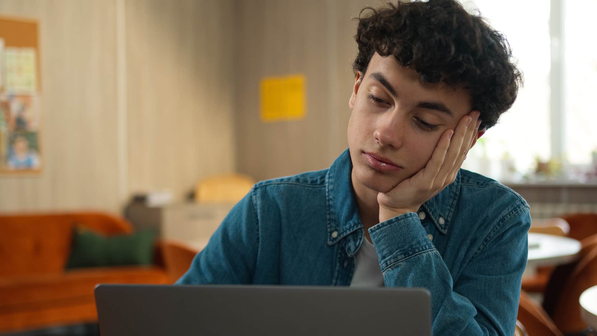 Upset teenage boy who never apologizes looking at his laptop.