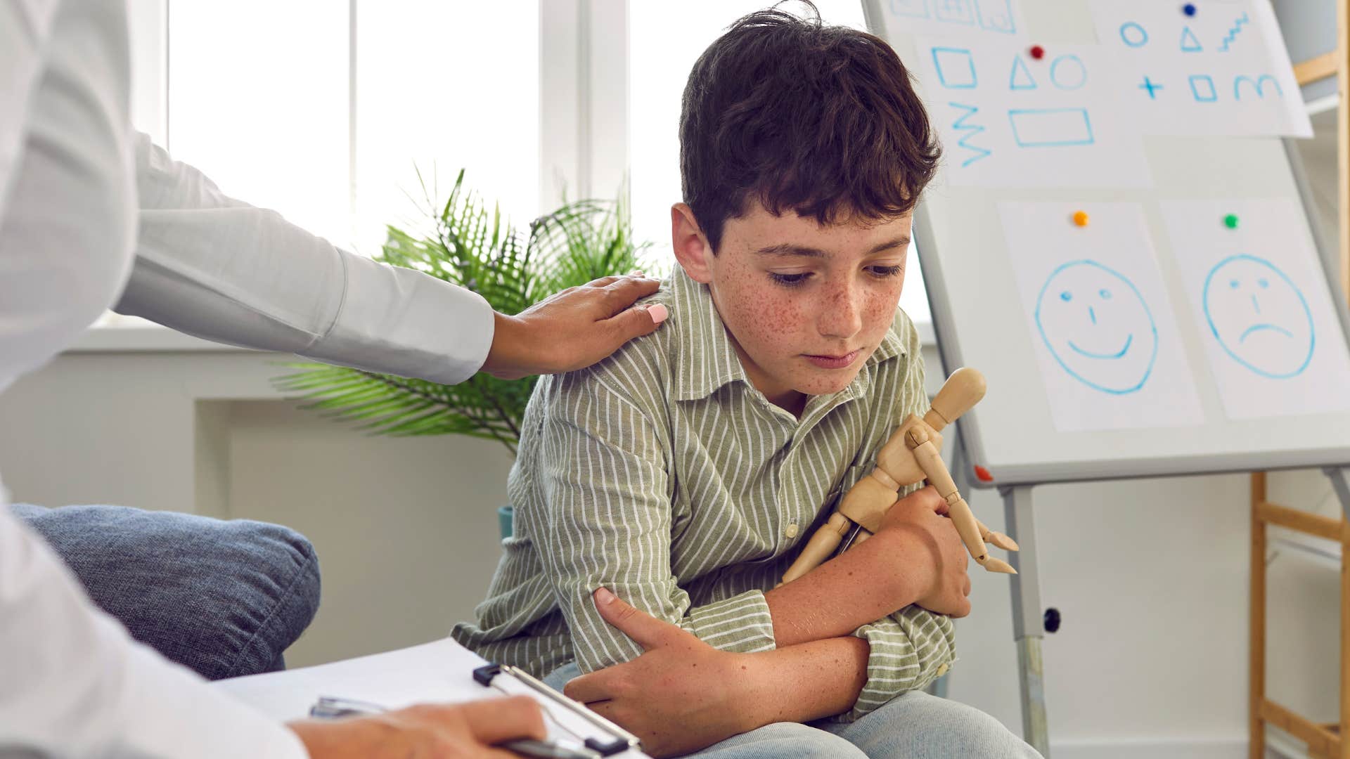 Upset little boy seeking attention next to a teacher.