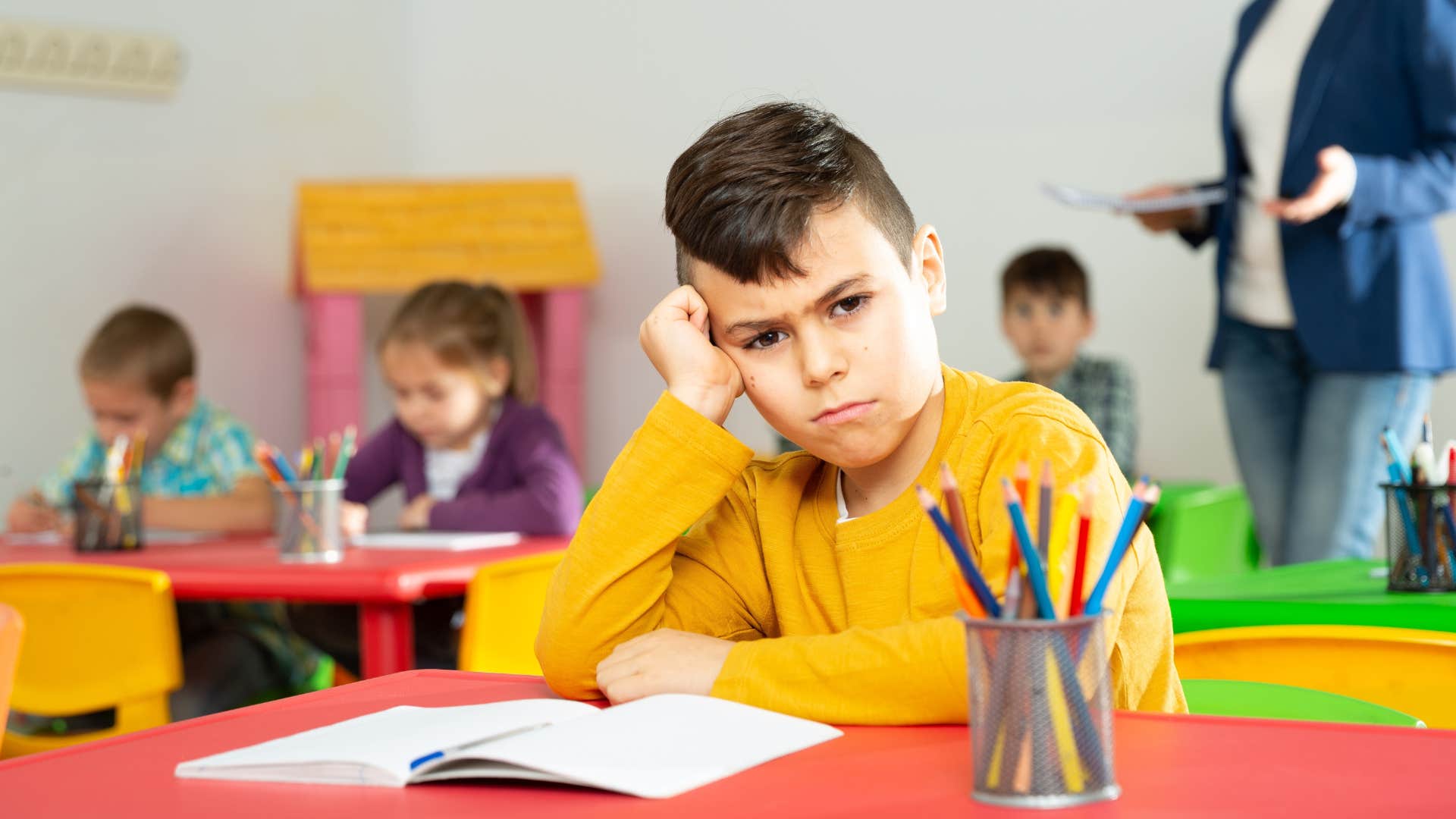 Upset boy talking back to a teacher in a classroom.