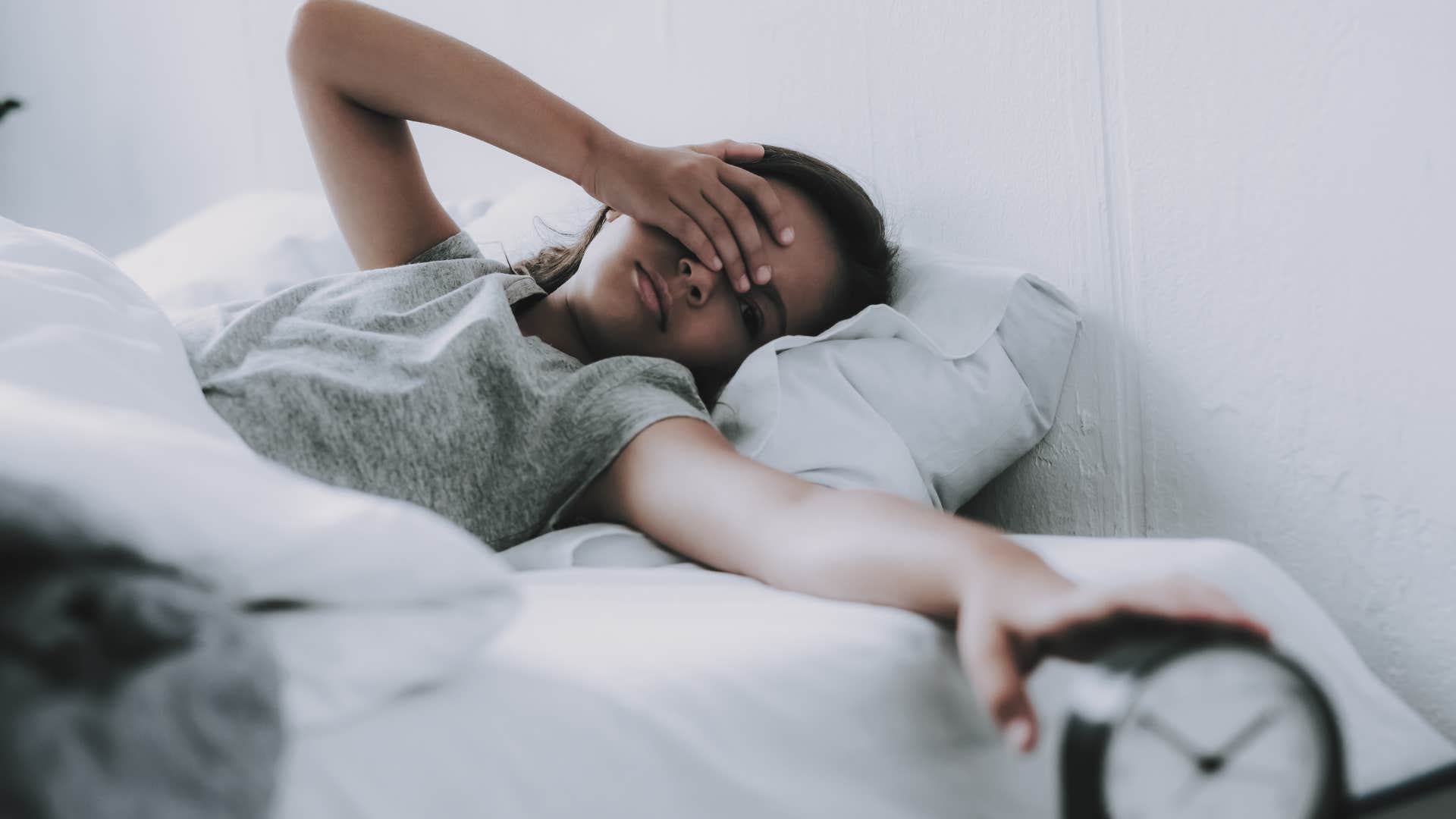 a woman sets her alarm clock so that she can wake up early and regrets it
