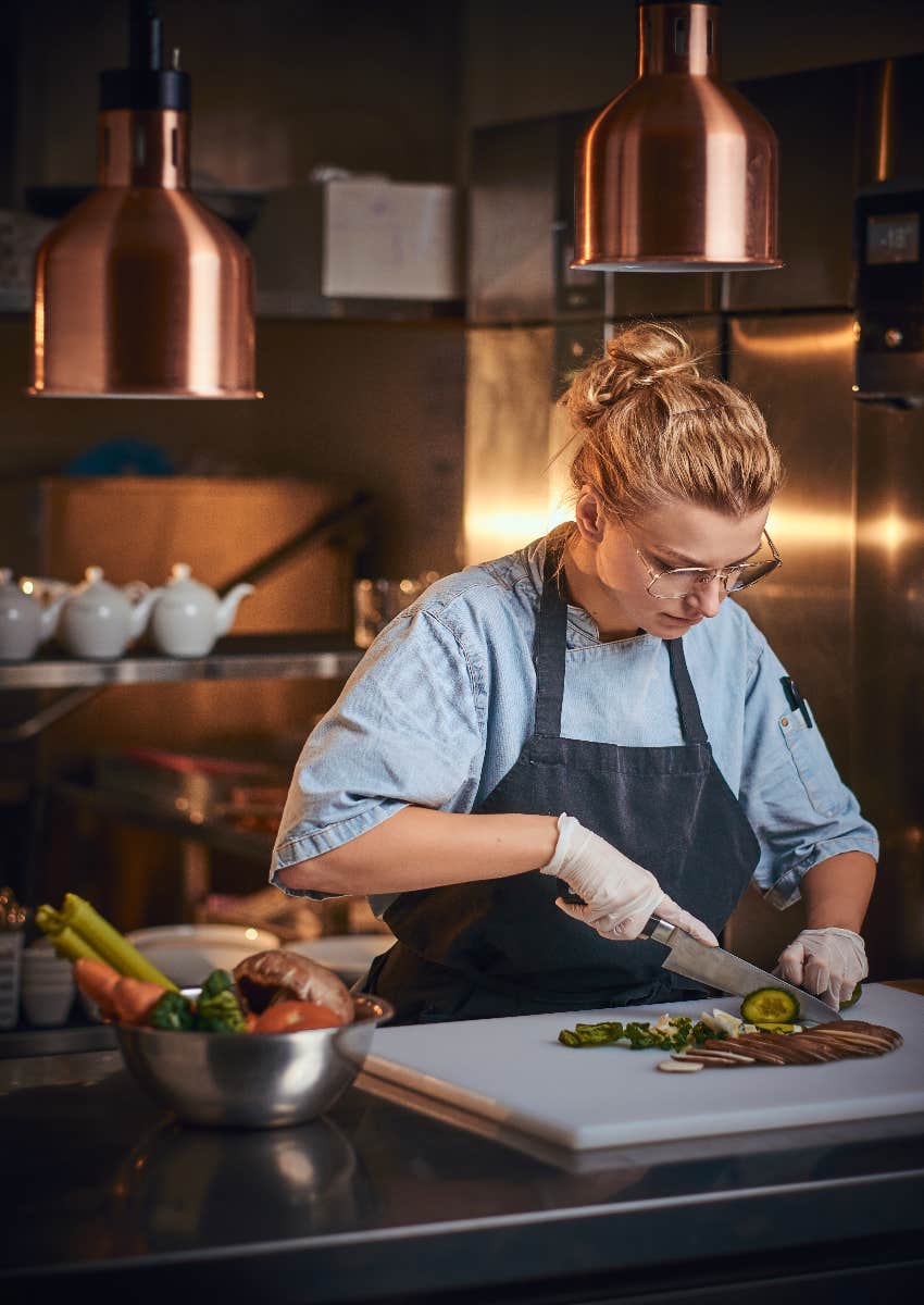 female chef chopping vegetables in professional kitchen