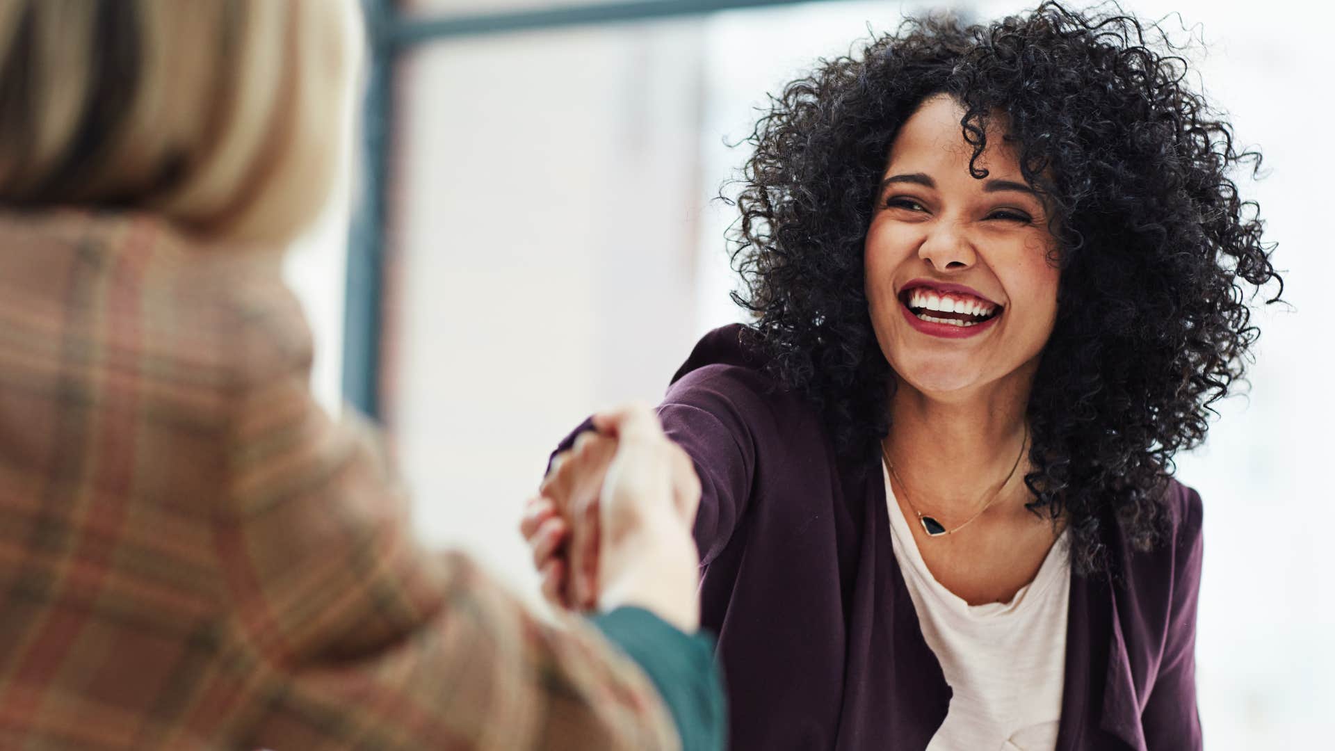 happy woman who has bigger priorities shaking a co-worker's hand